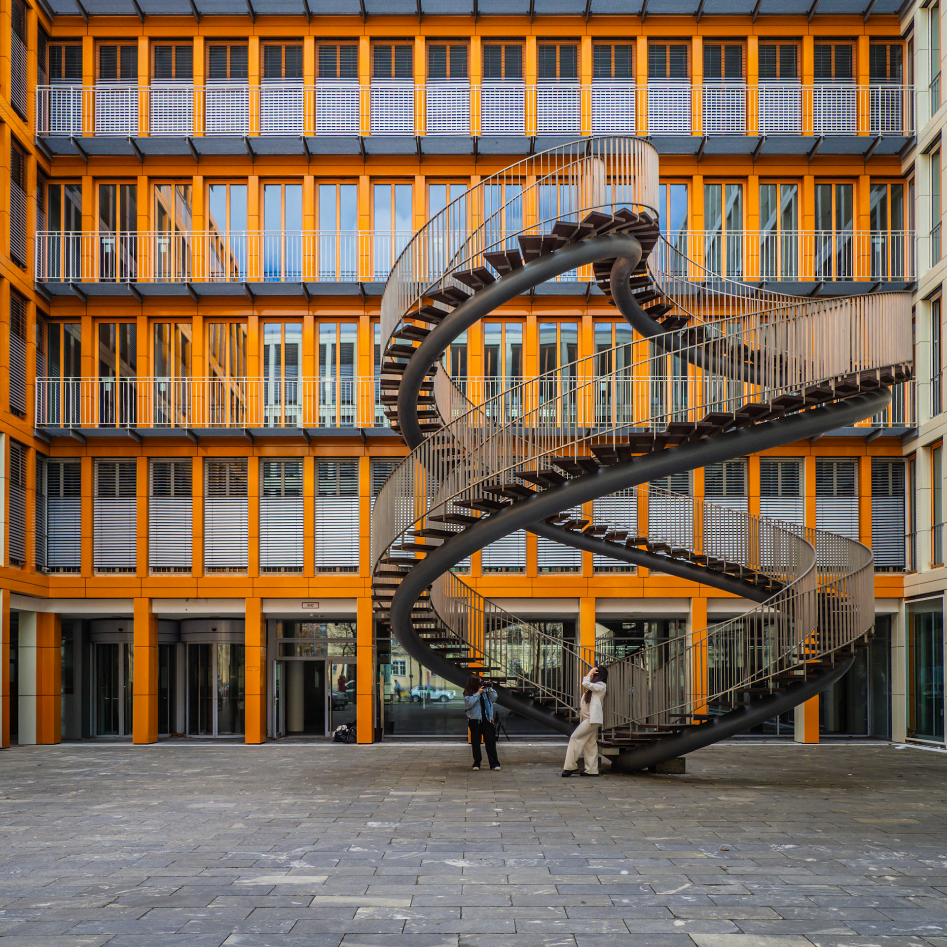 A model poses for the camera during a photoshoot underneath an endless staircase in Munich