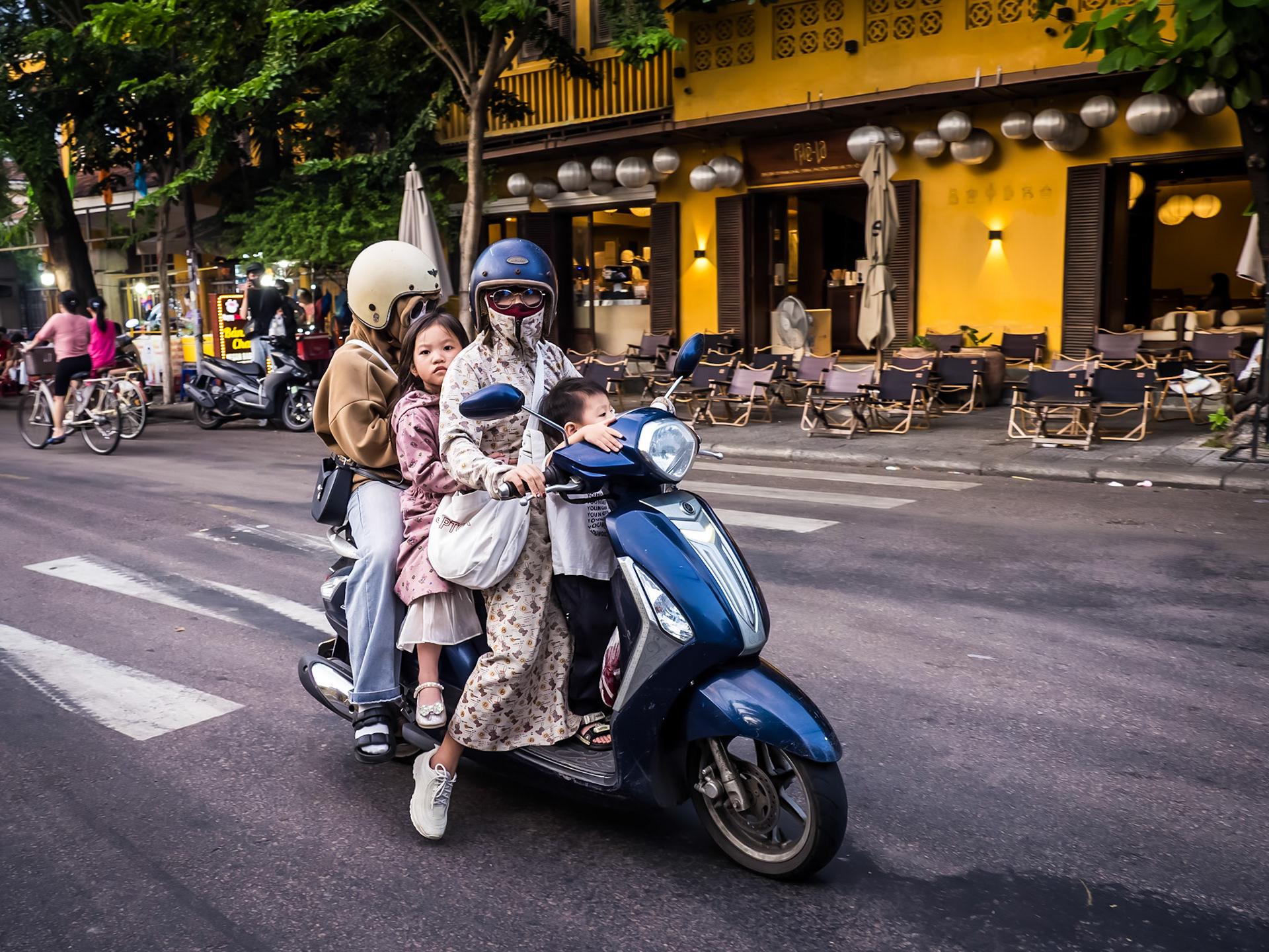 On a single moped a family of four speed through the centre of Hoi An on their way home