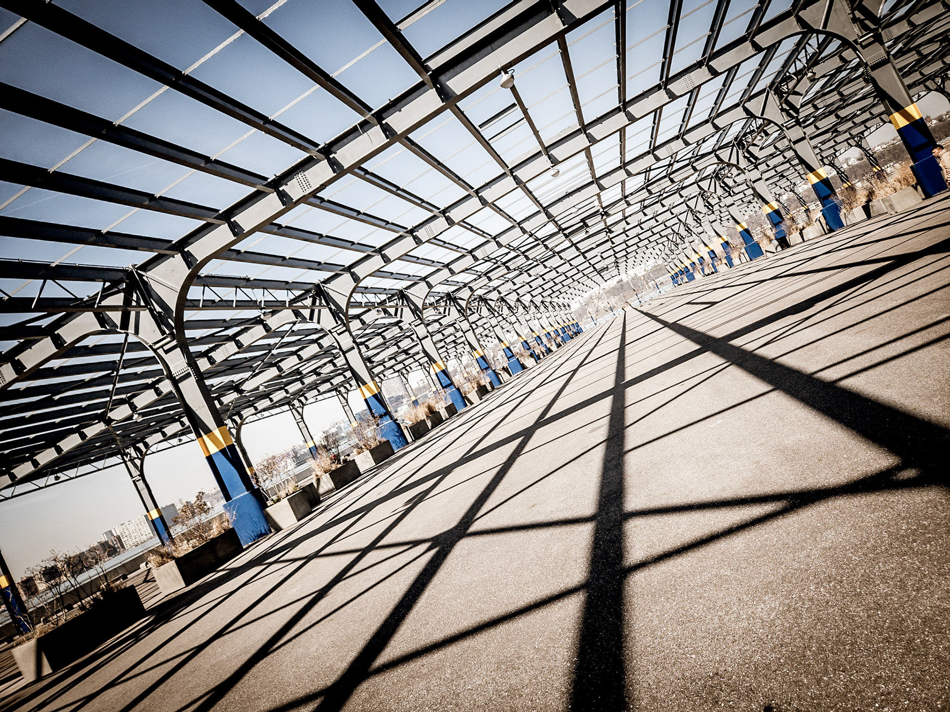 Steel girders and the shadows they cast all lead the eye to the very end of a deserted pier on the Hudson river in New York