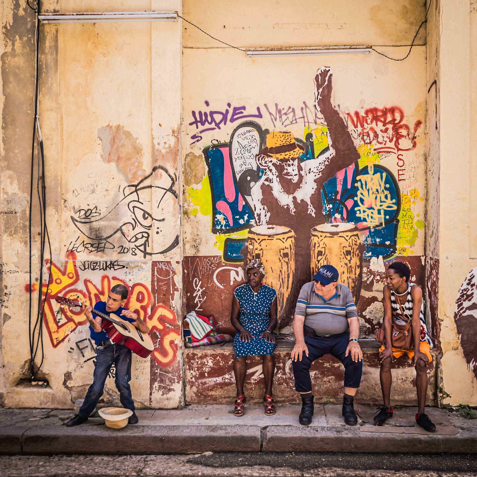 A busker plays the guitar in front of an eclectic audience on a Havana street