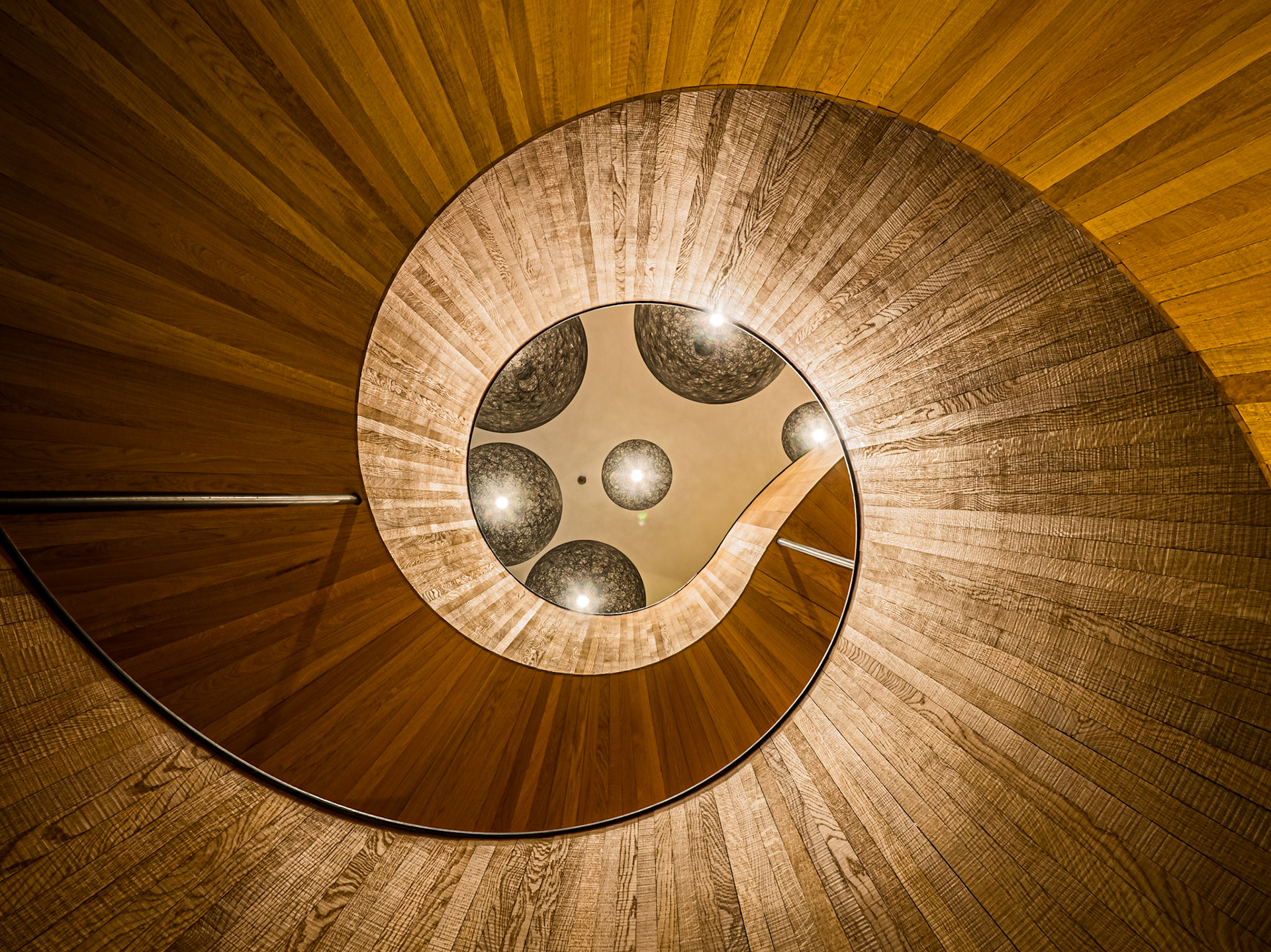 A beautiful wooden staircase spirals upwards with geometric perfection