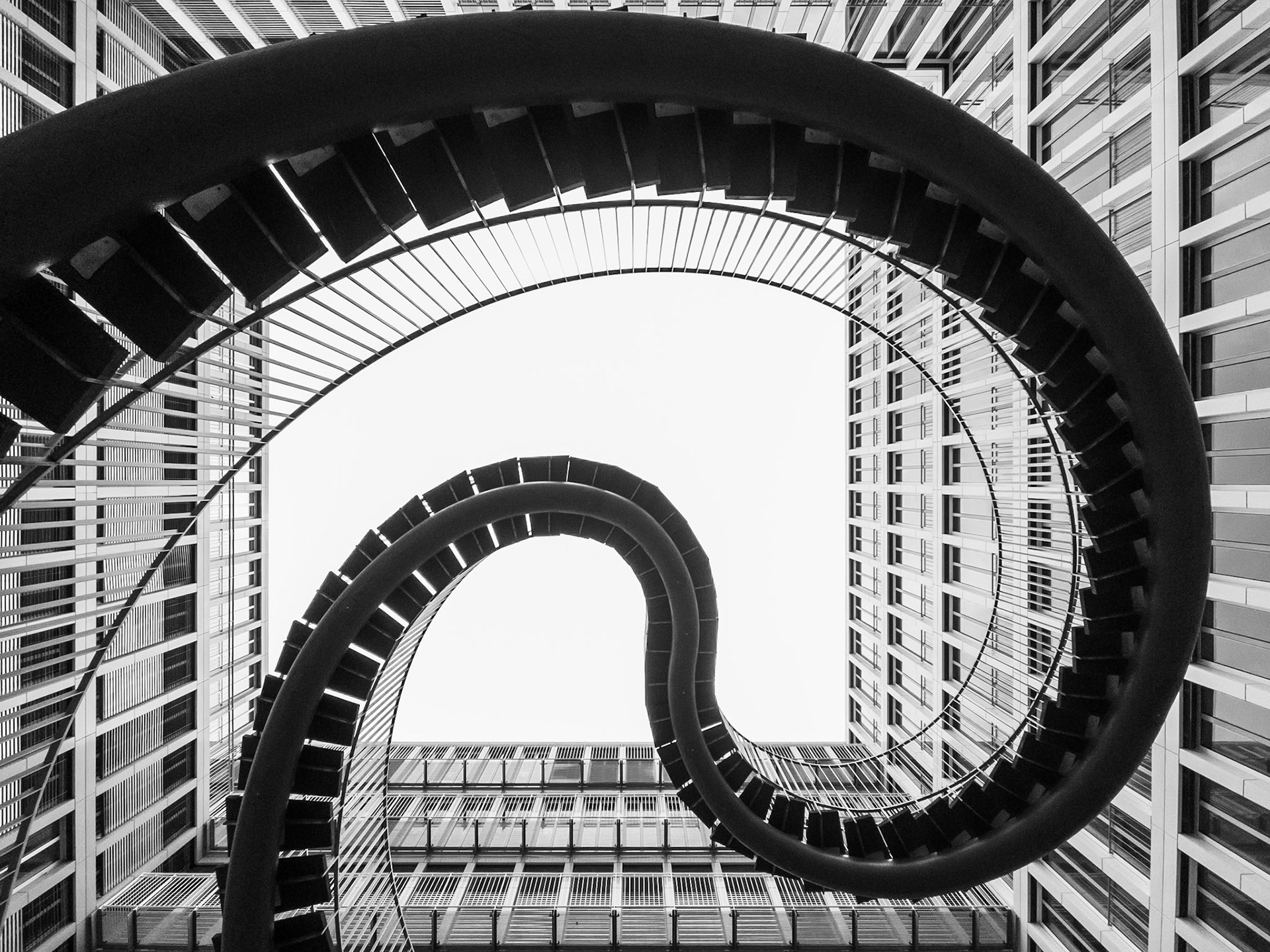 An endless staircase climbs into the sky in the courtyard of an office block in Munich