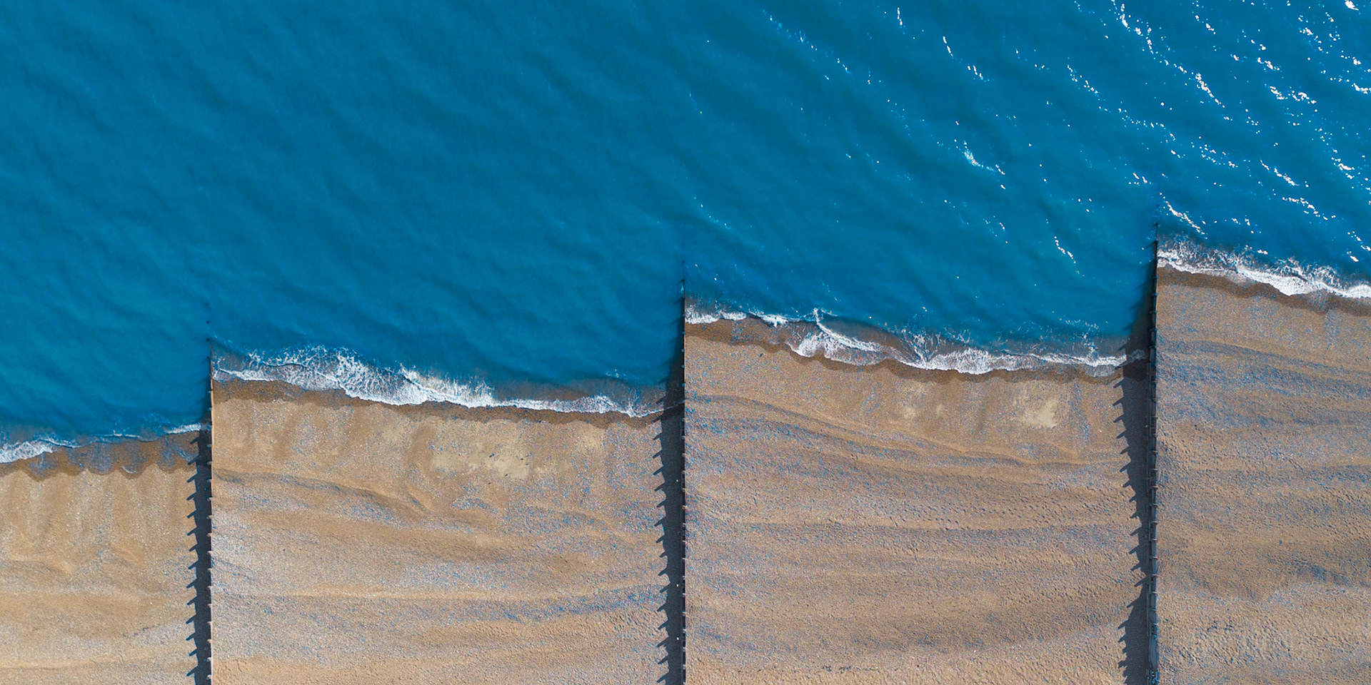Waves gently lap against the pebble shoreline of a beach along the southern coast of England