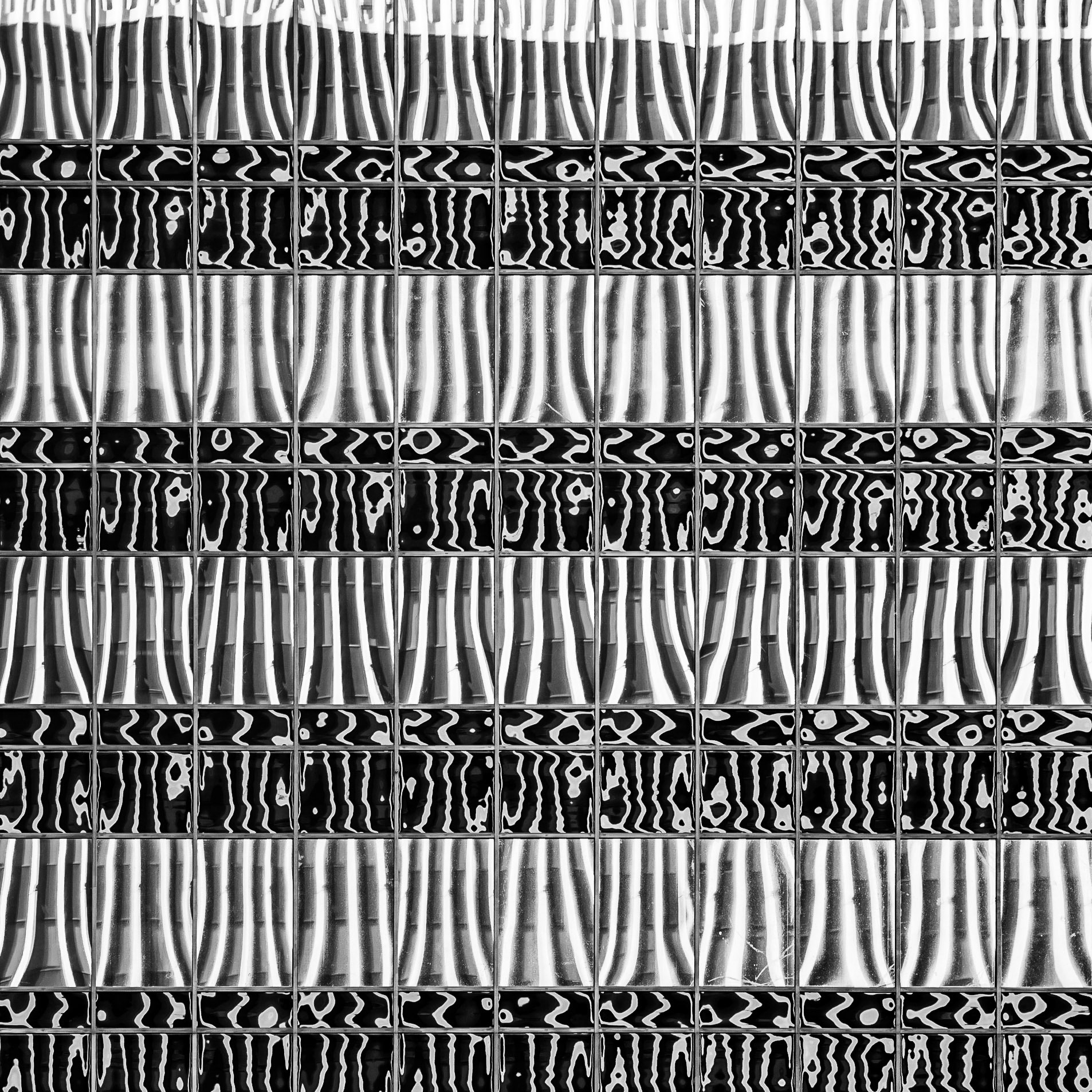 The vertical lines of an adjacent building are warped by the the imperfect windows panes of a tall building in San Diego