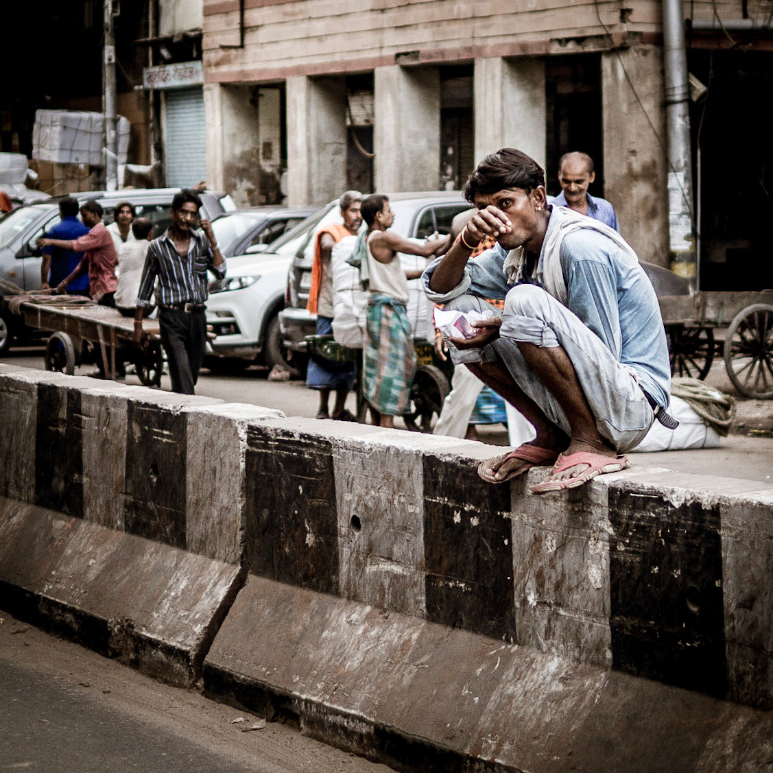 A man eats his meal whilst perched on the central reservation of a road in the Chandni Chowk district of New Delhi