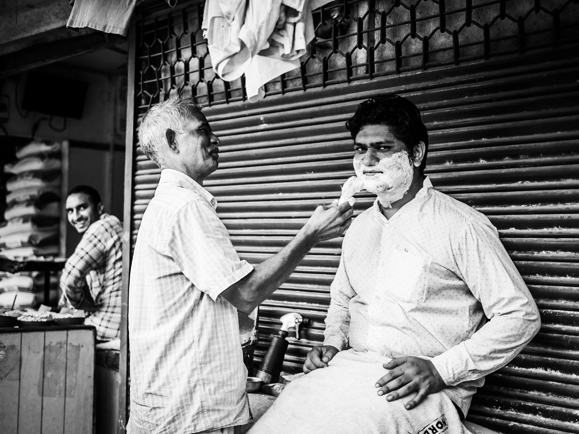 A barber attends to a customer inside the spice market of the Chandni Chowk district of New Delhi