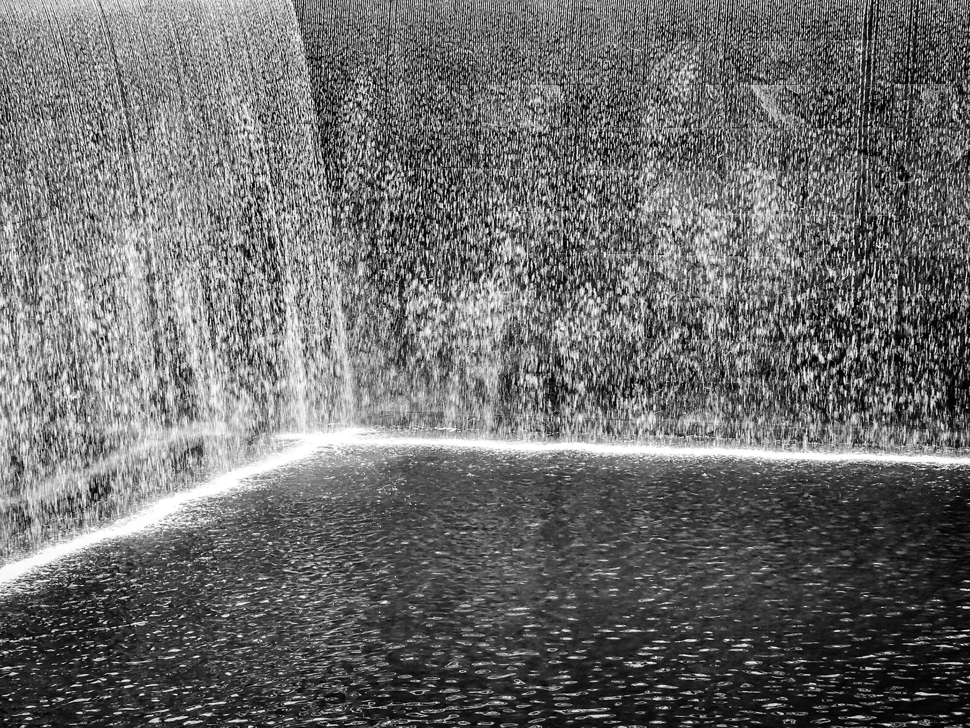 Two walls of cascading water fall into the tranquil ponds of the 9/11 memorial in New York City
