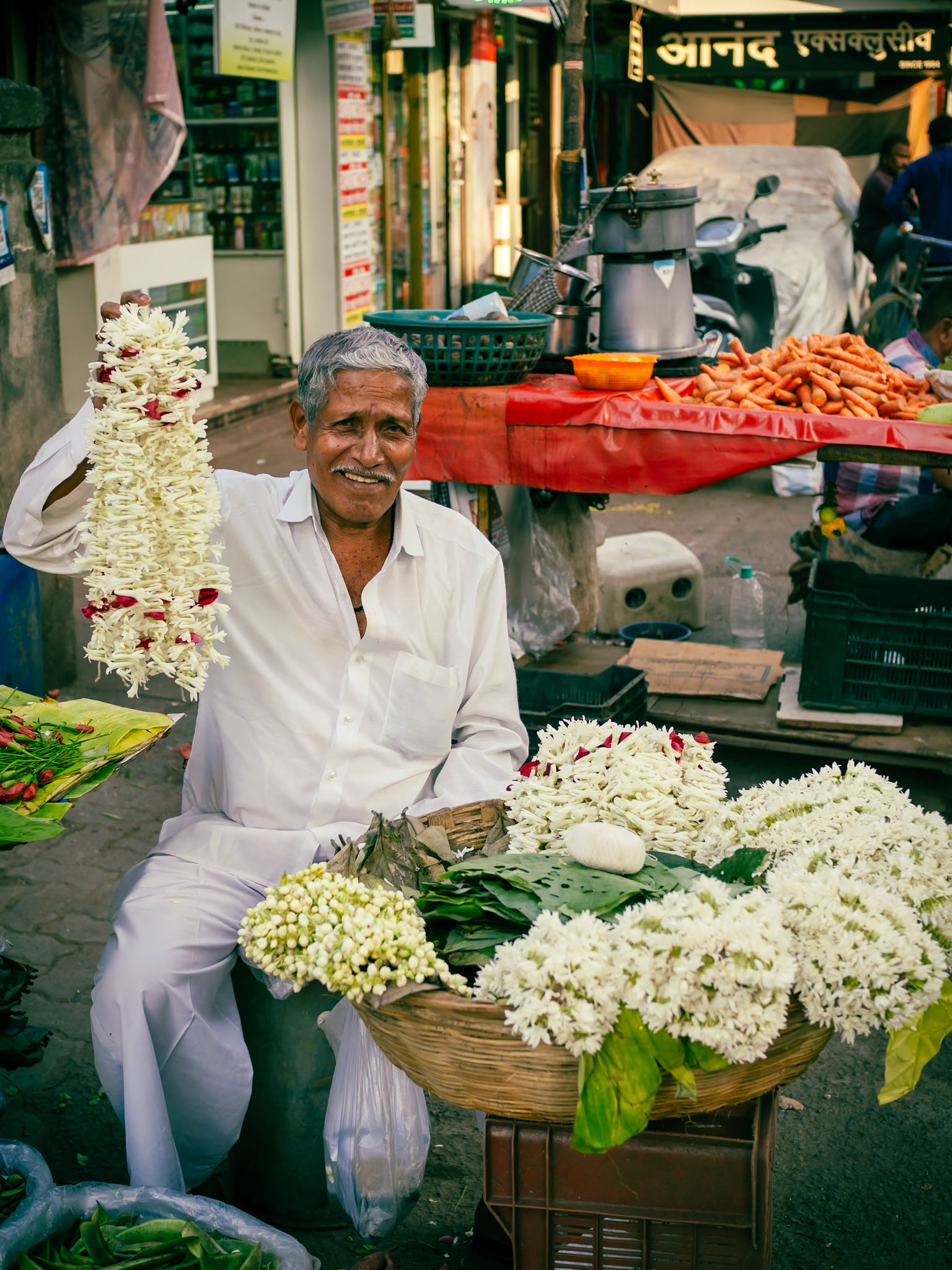 A stallholder in a Mumbai street market shows off his latest creation, a garland made from fresh flowers