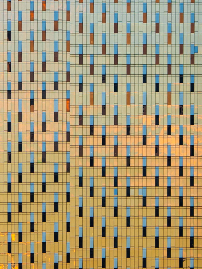 The colourful window panes of a tall skyscraper in Manhattan reflect the evening sunset