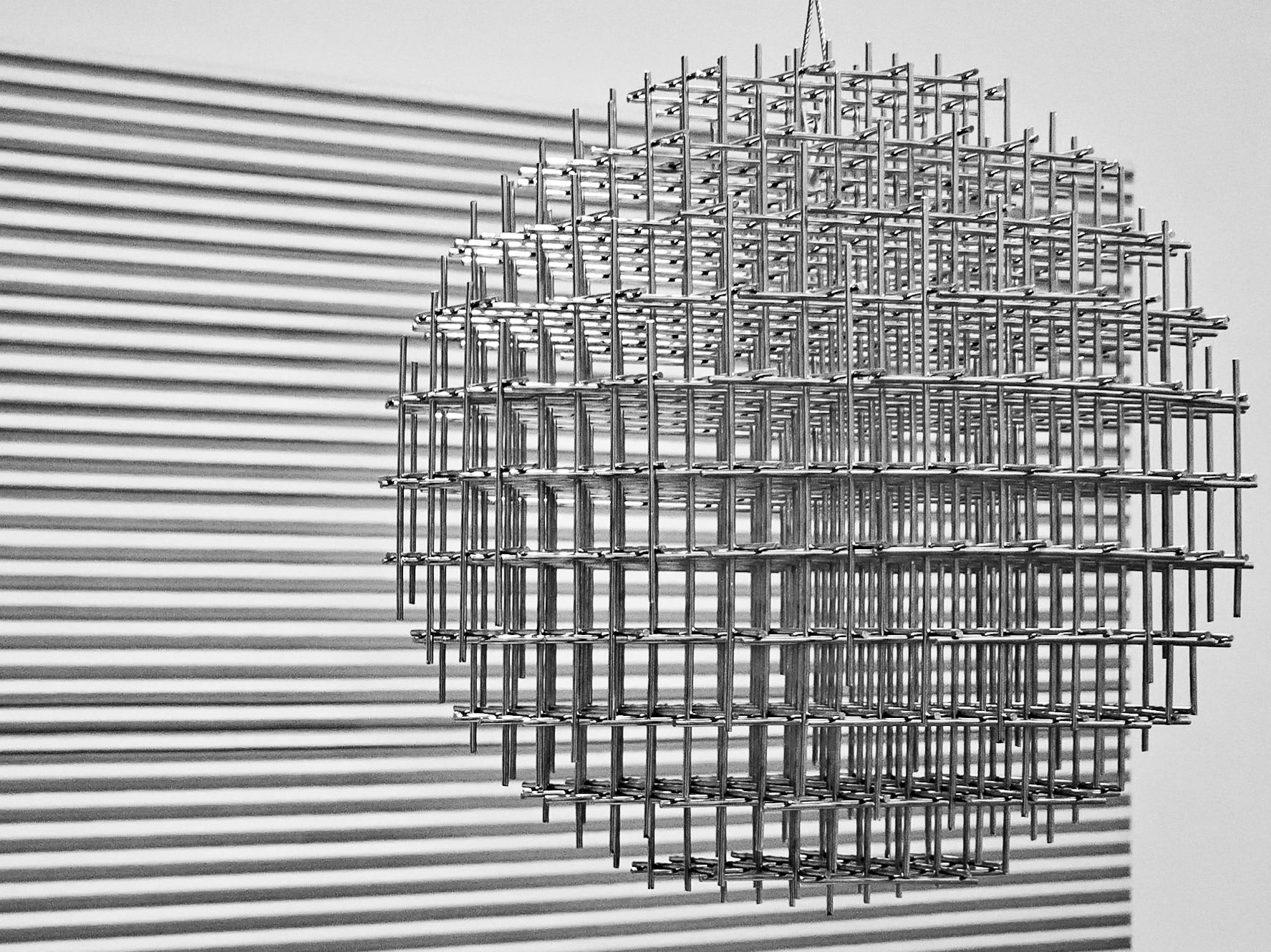 A sphere-like structure comprised of a three dimensional lattice of steel rods set aginst a horizontal stipres