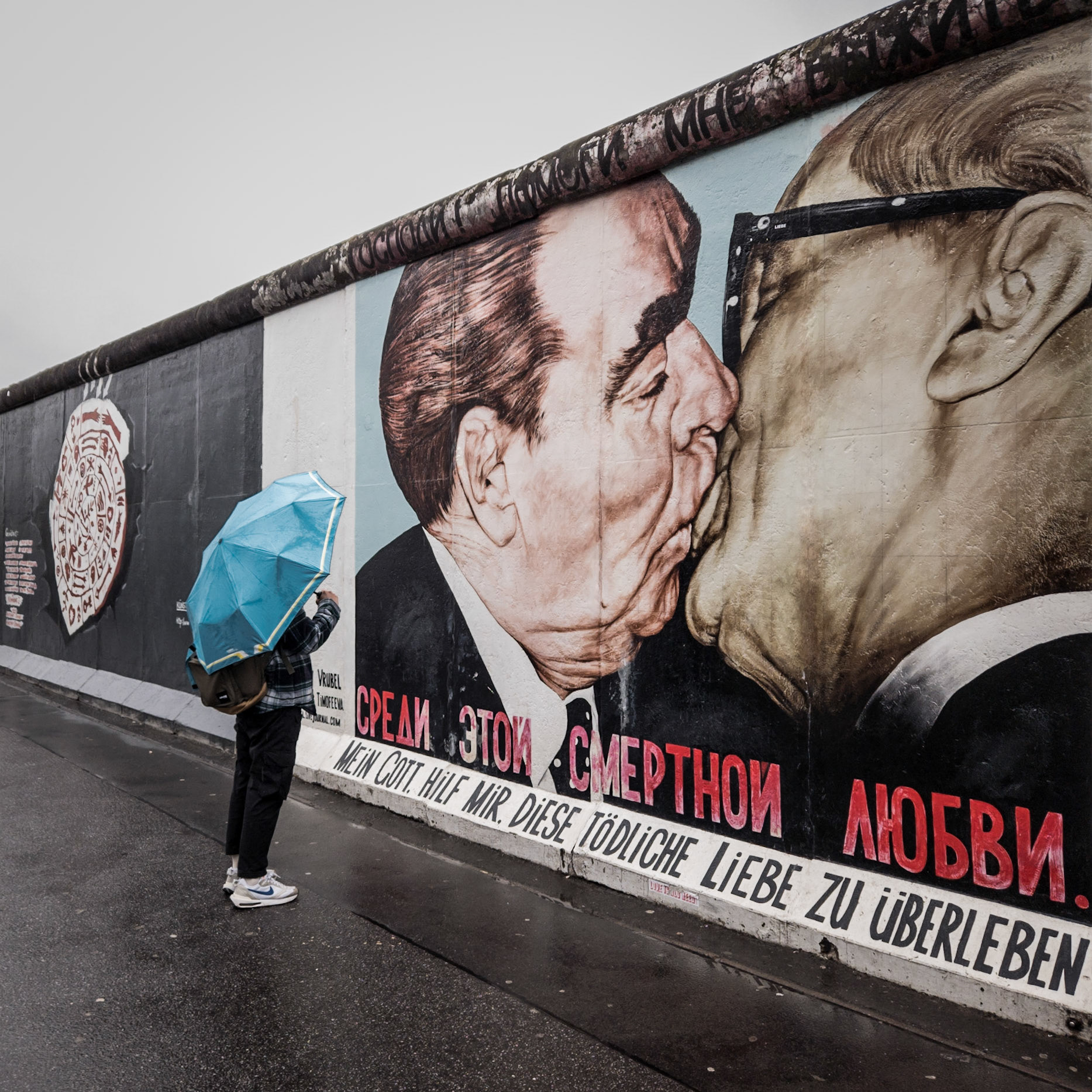 A tourist stares at a mural on the Berlin Wall of former Soviet leader Leonid Brezhnev and German Democratic Republic leader Erich Honecker