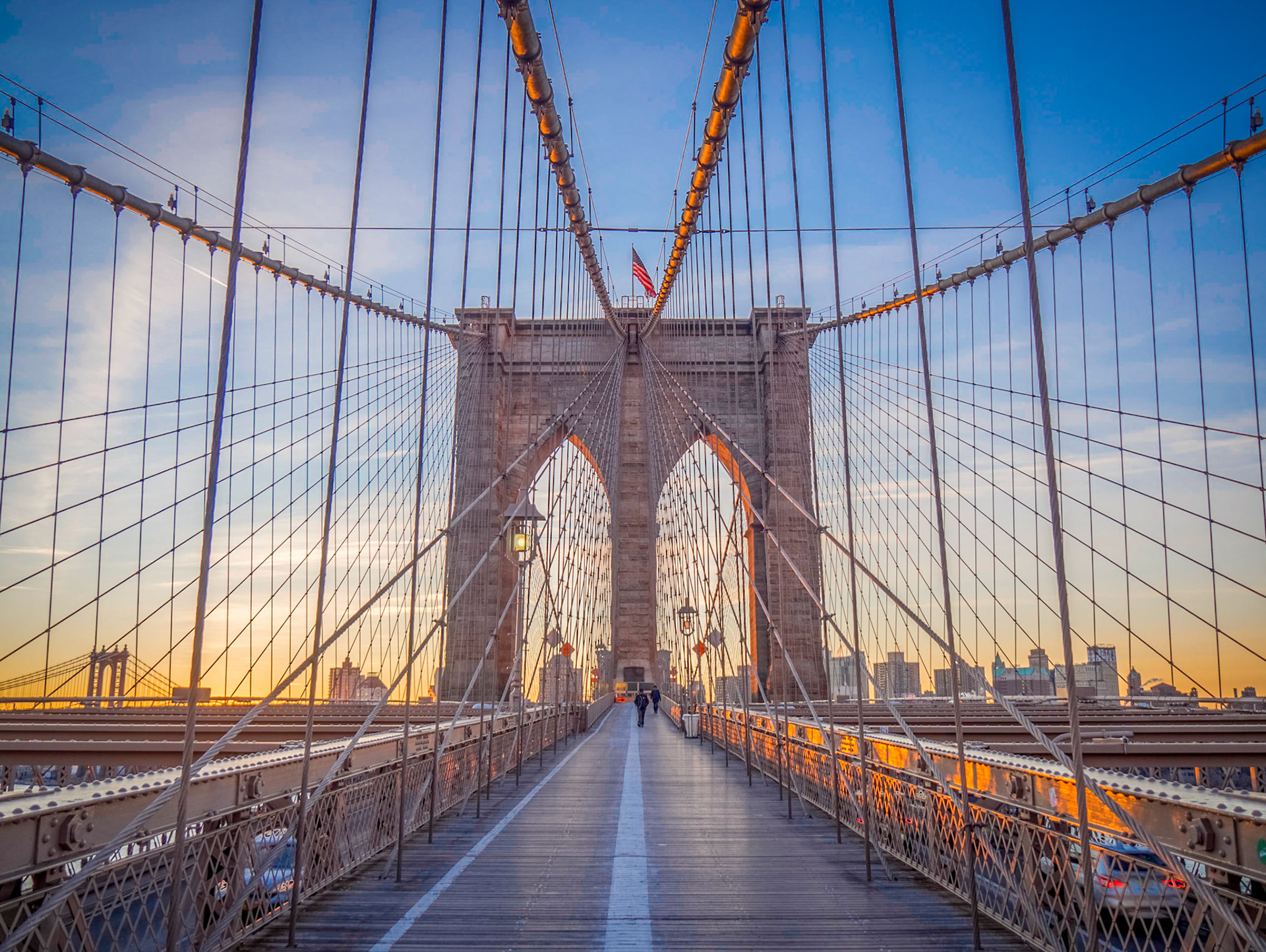 Dawn rises behind the towers and cables of Brooklyn Bridge, New York