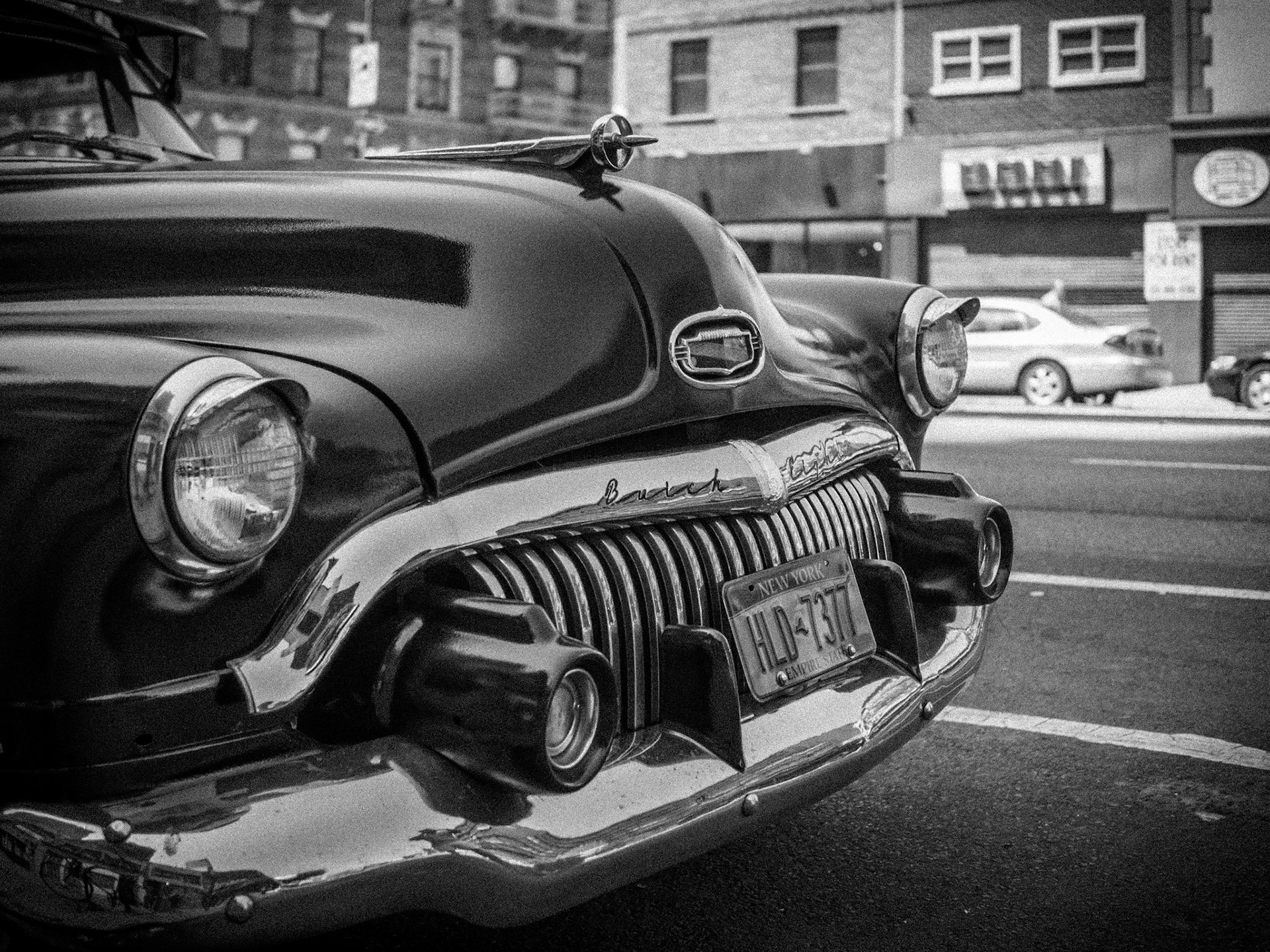 A vintage Buick automobile stands idle on a street in the Bowery district of Manhattan, New York