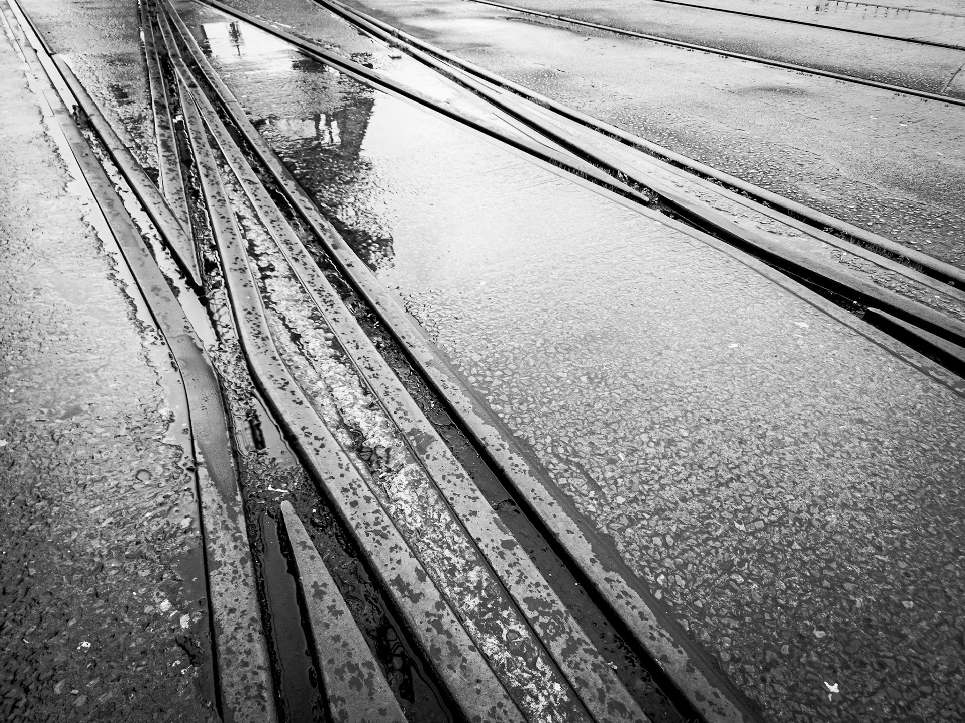 Sunken rail tracks cross eachother on a derelict dockside in central Bristol on a rainy day