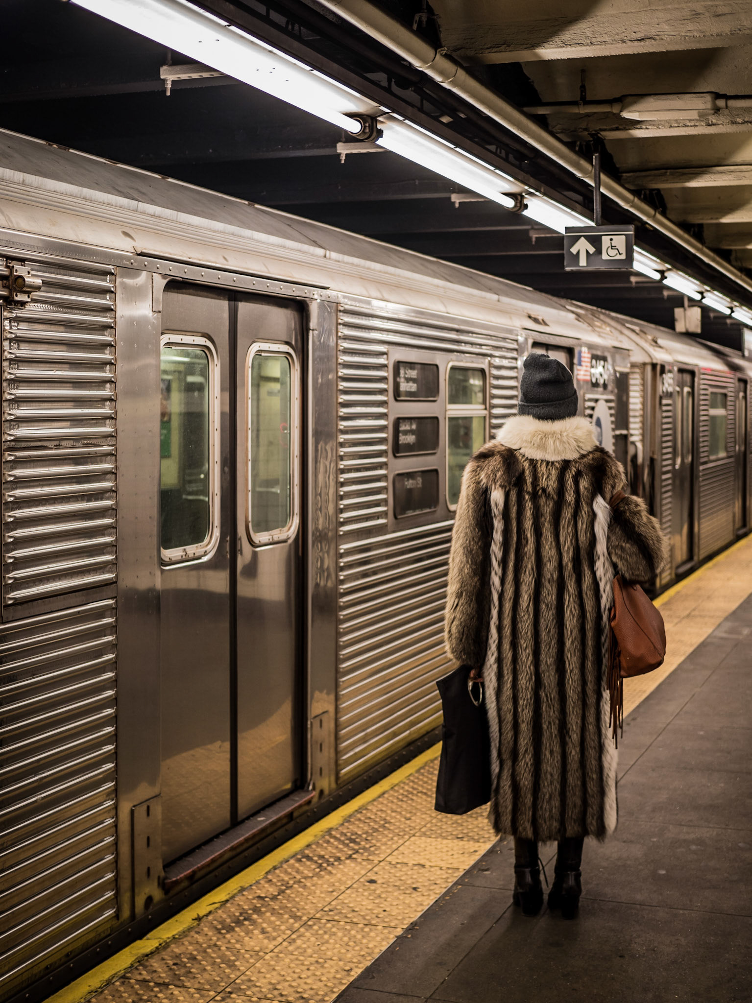 A well-dressed lady waits for  the doors to open on a subway train at 168th Station in Manhattan, New York