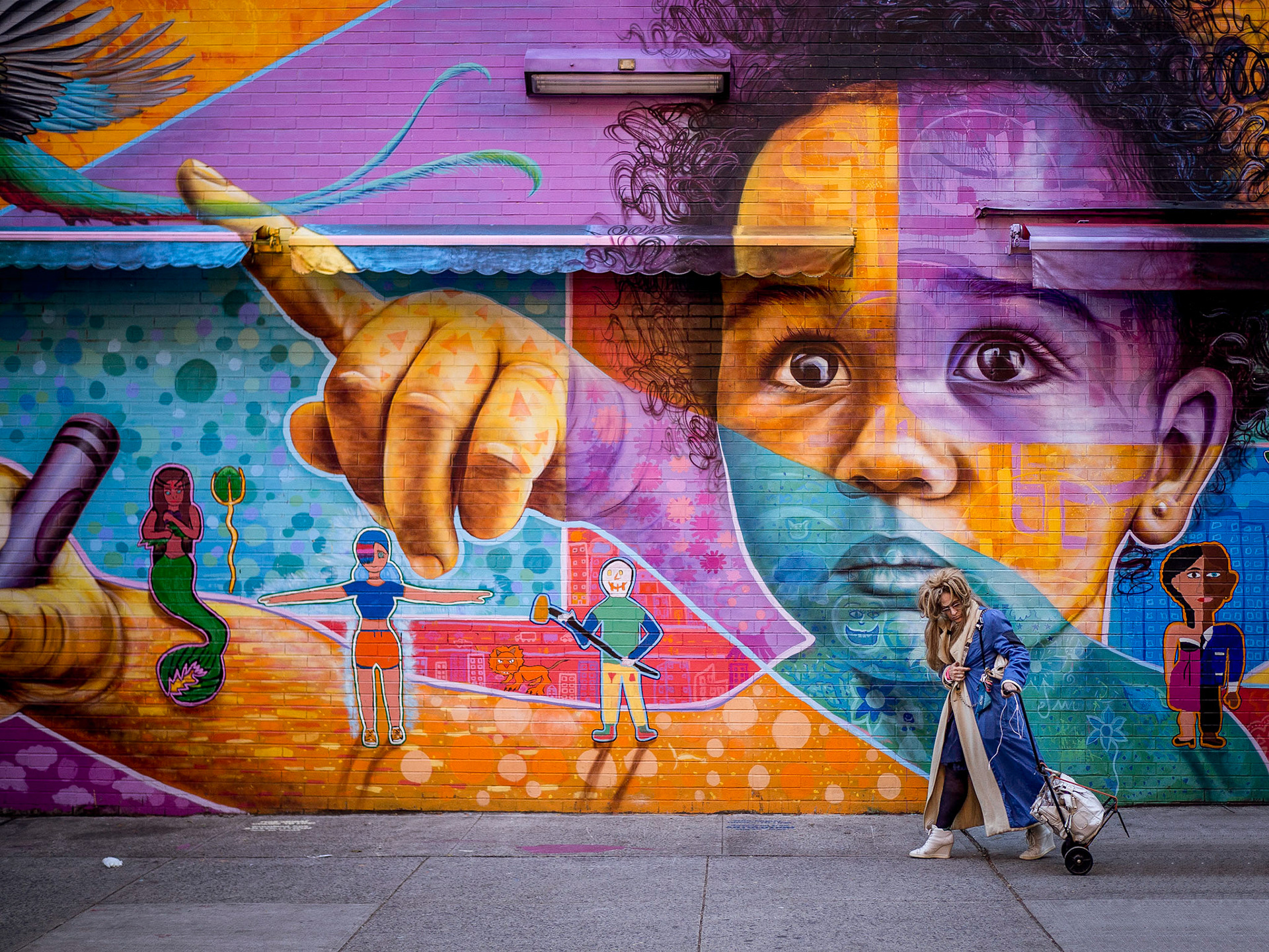 A shopper walks in front of a poignant mural in the Lower East Side district of Manhattan, New York