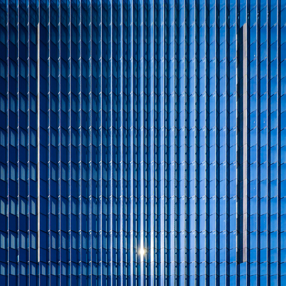 The stark geometry of a downtown Los Angeles office building, with its repeating patterns and cool blue palette, punctuated by a burst of sunlight