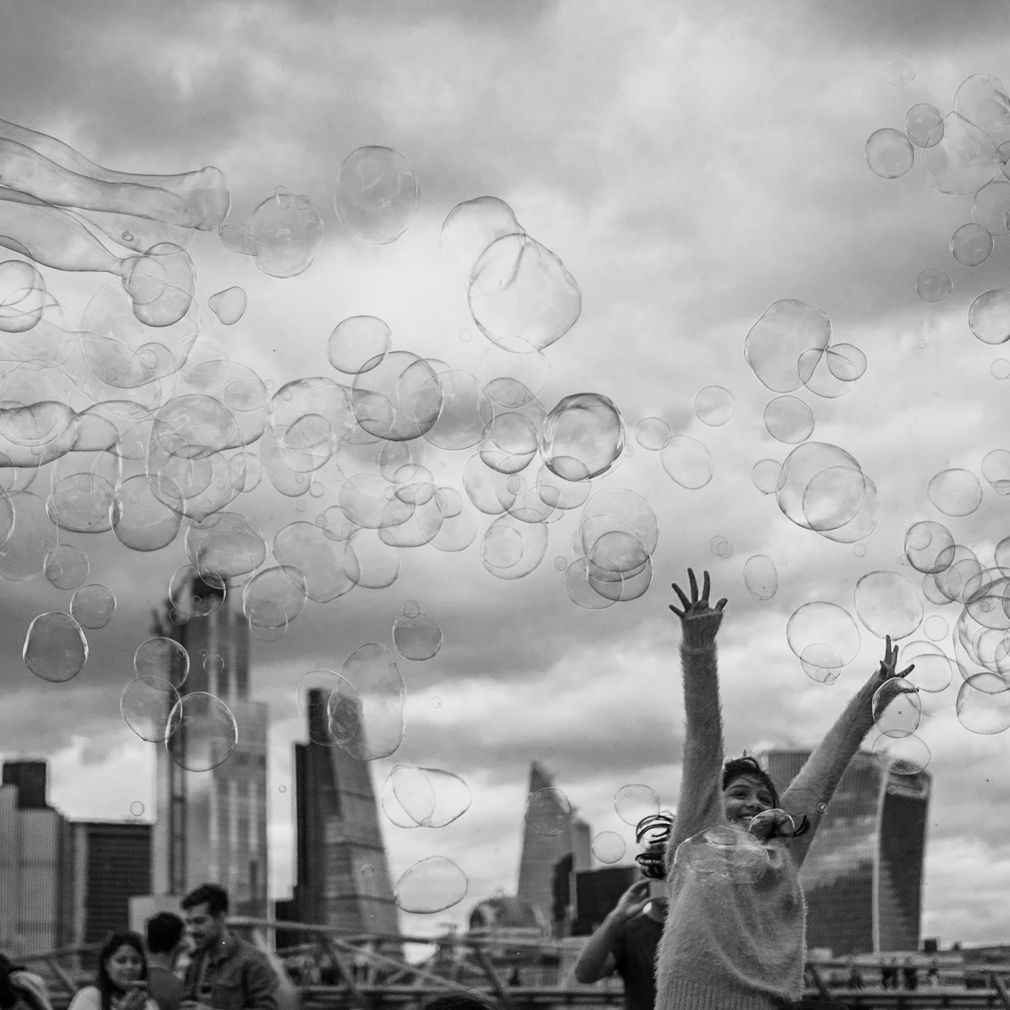 Children shriek with joy trying to catch bubbles on the south bank of the River Thames in London