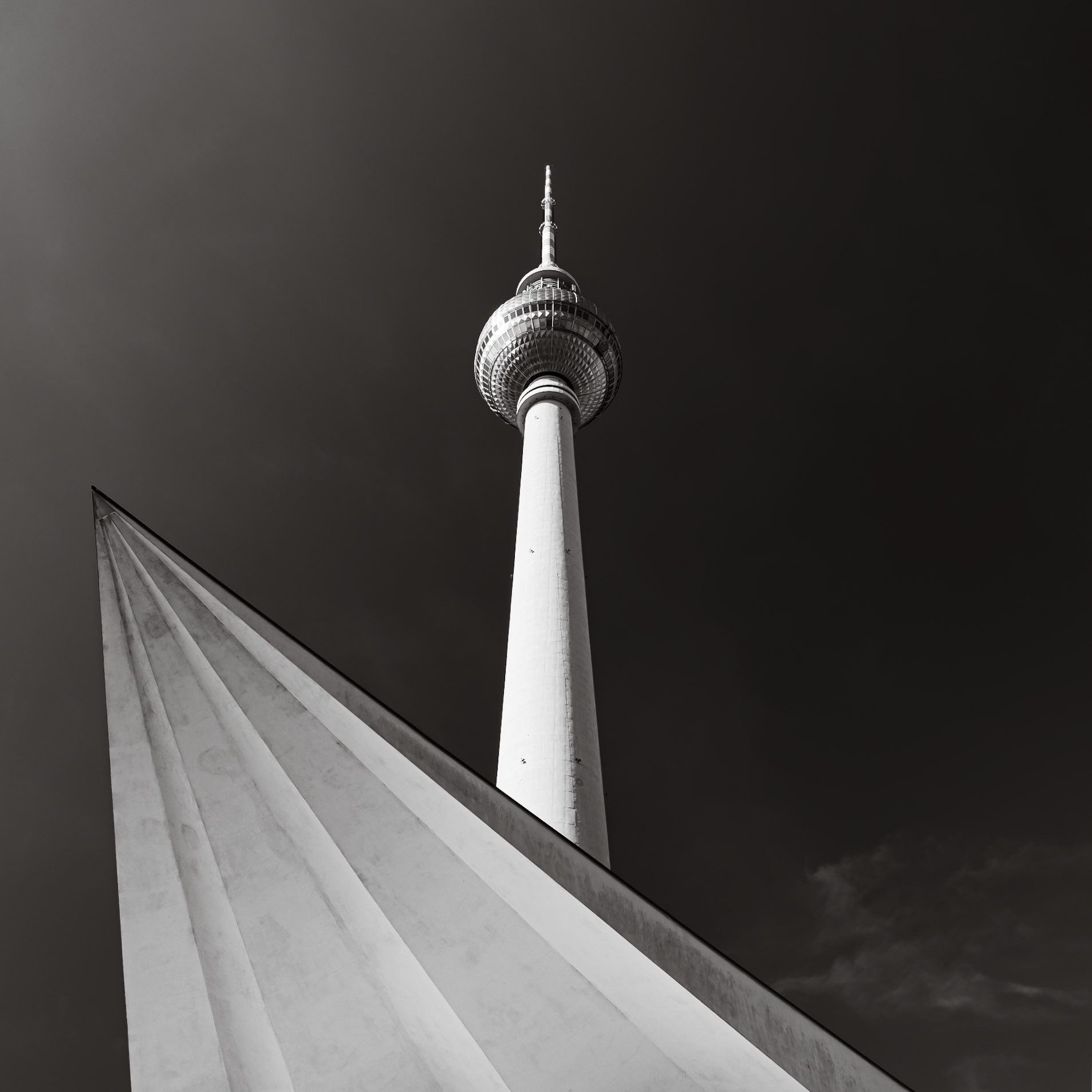 The stark Eastern-European 1960s architecture of the Fernsehturm just into the clear sky over the city of Berlin
