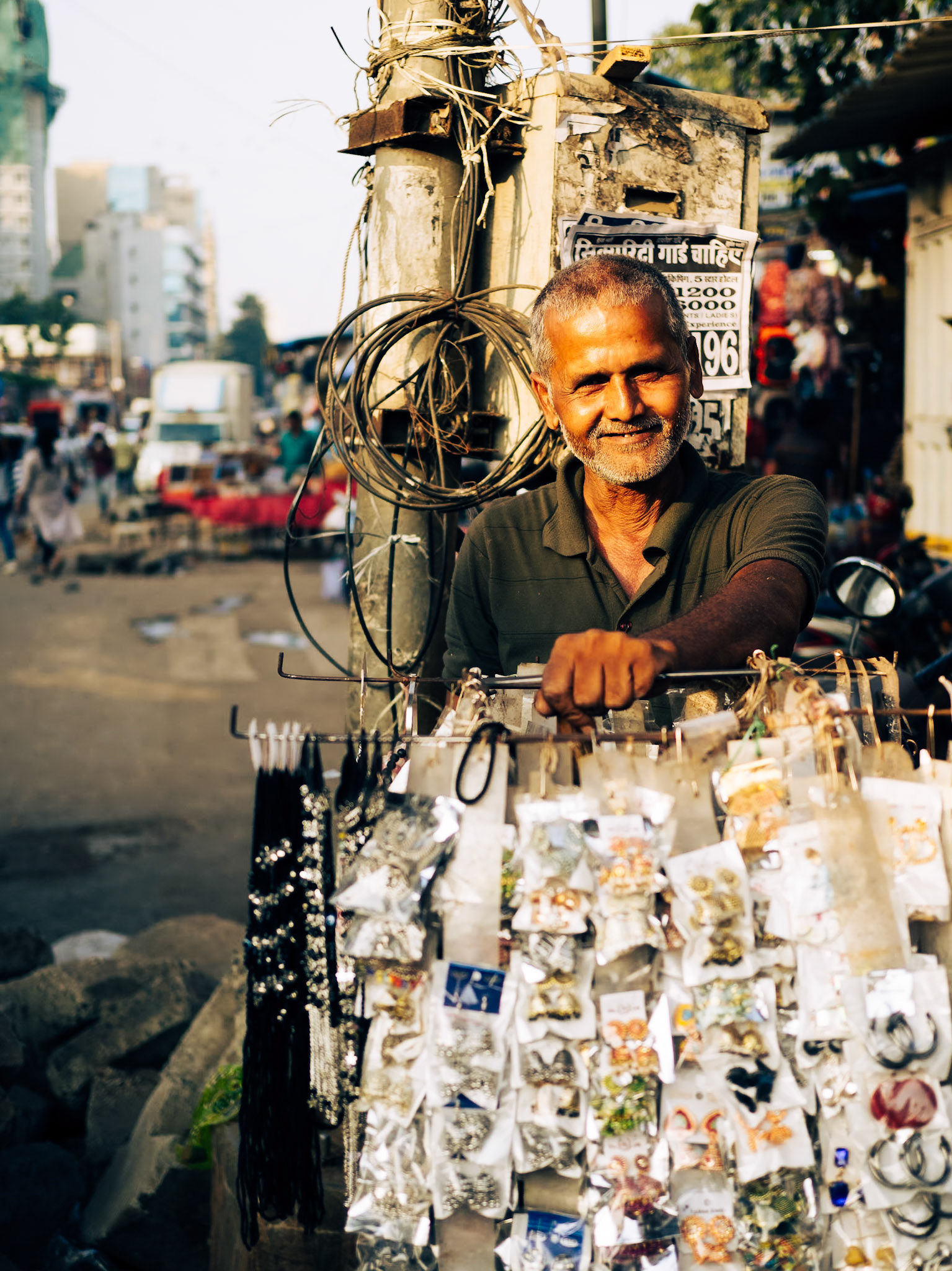 A street vendor proudly poses with his jewellery for sale as the sun sets over the streets of Mumbai