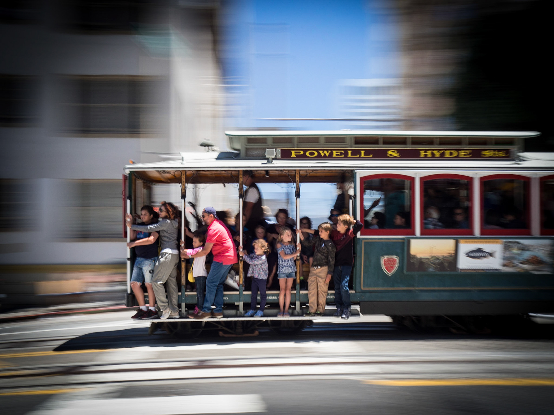 Passengers hold on tight as  an iconic cable car speeds through the streets of San Francisco