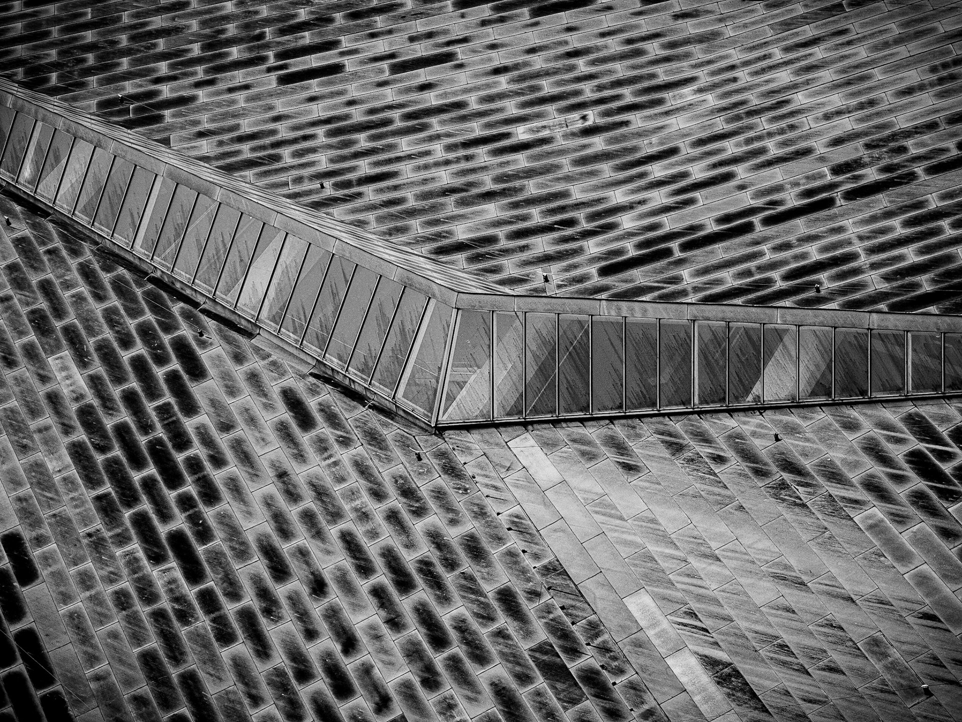 Copper tiles flow from a central skylight down either side of a building in central Manchester