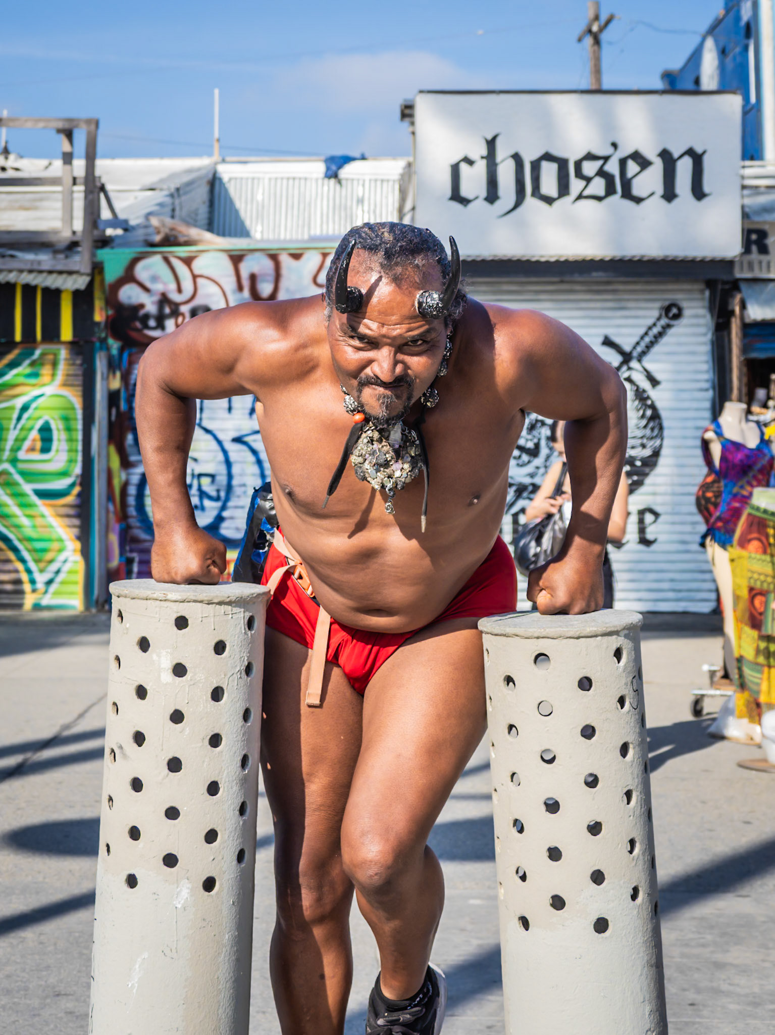 A local body-builder shows off his strength with a set of add-hoc press-ups on Venice Beach boardwalk in California