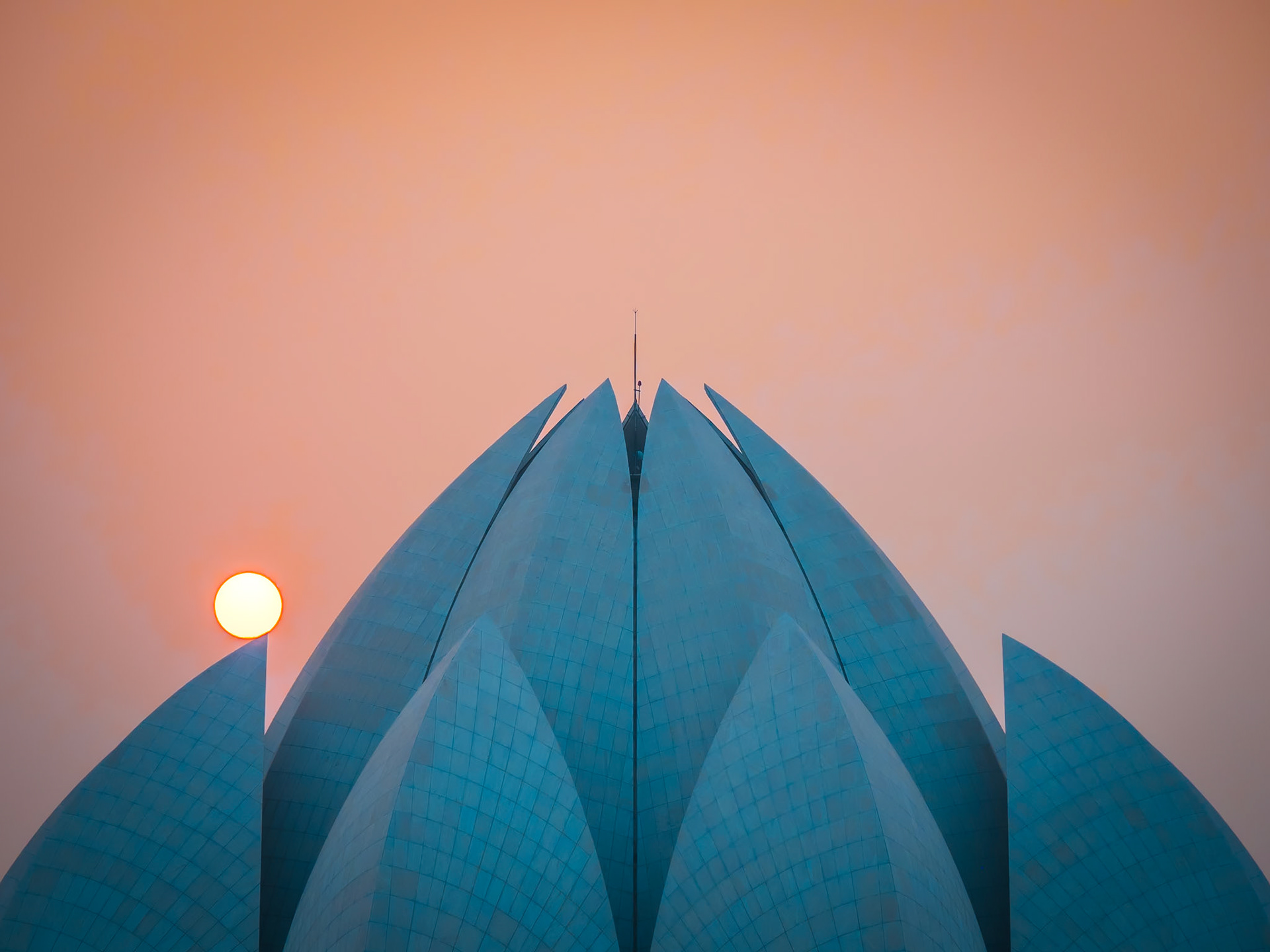 The setting sun rests on one of the tips of the Lotus Temple in New Delhi