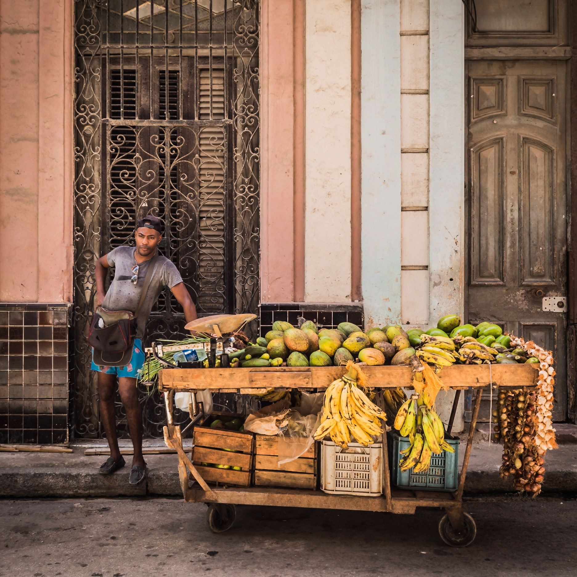 A street-seller awaits his next customer as he stands next to his grocery-laden trolley on one of Havana's streets