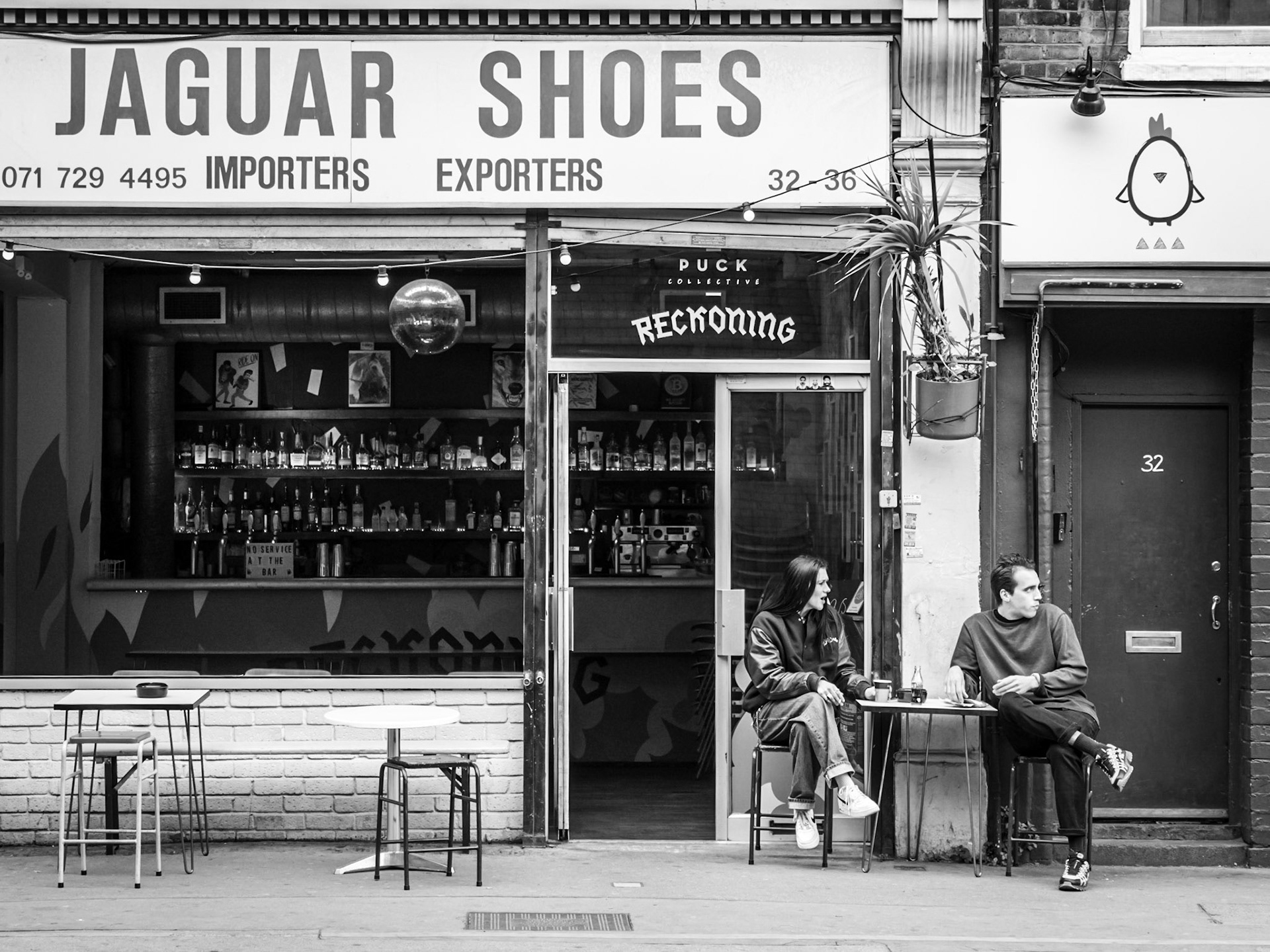 Coffee is interrupted for a couple in Shoreditch as their attention is diverted to events unfolding down the street