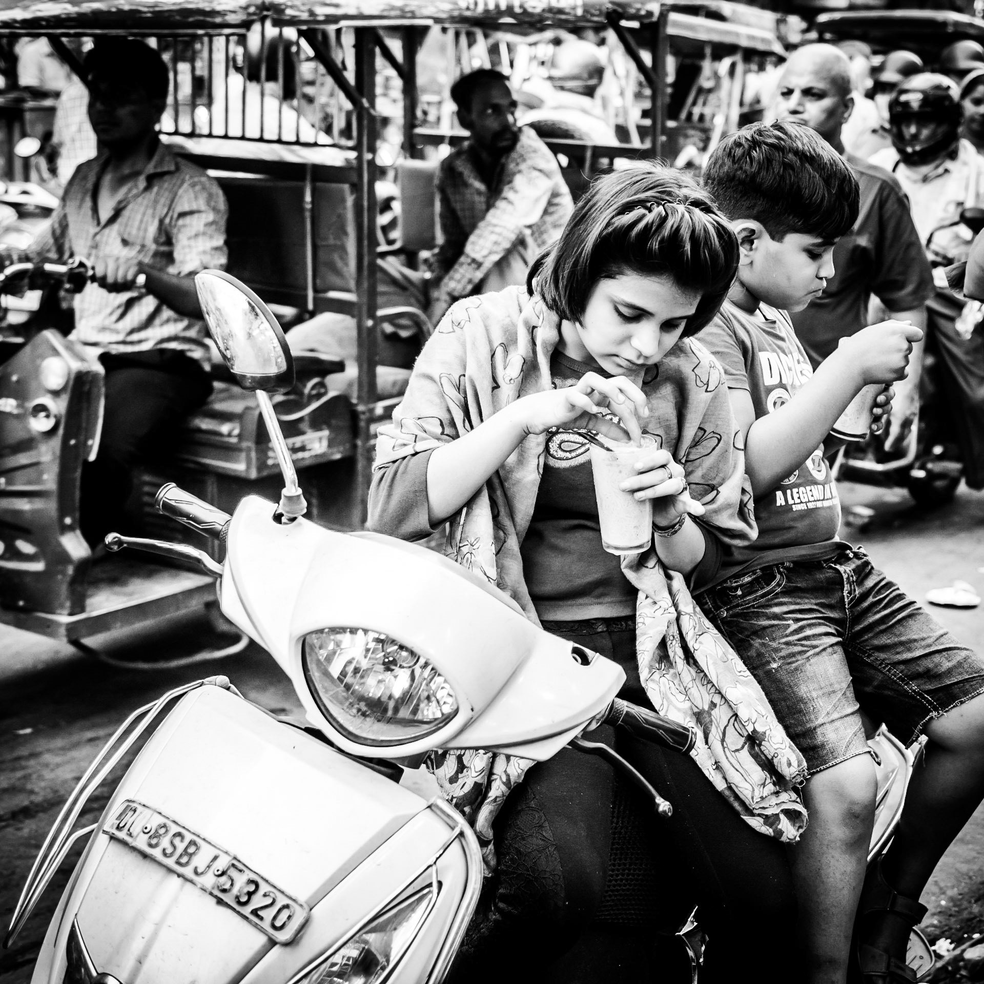 Two children have an afternoon treat whilst surrounded by the chaotic traffic in the Chandni Chowk market district of New Delhi