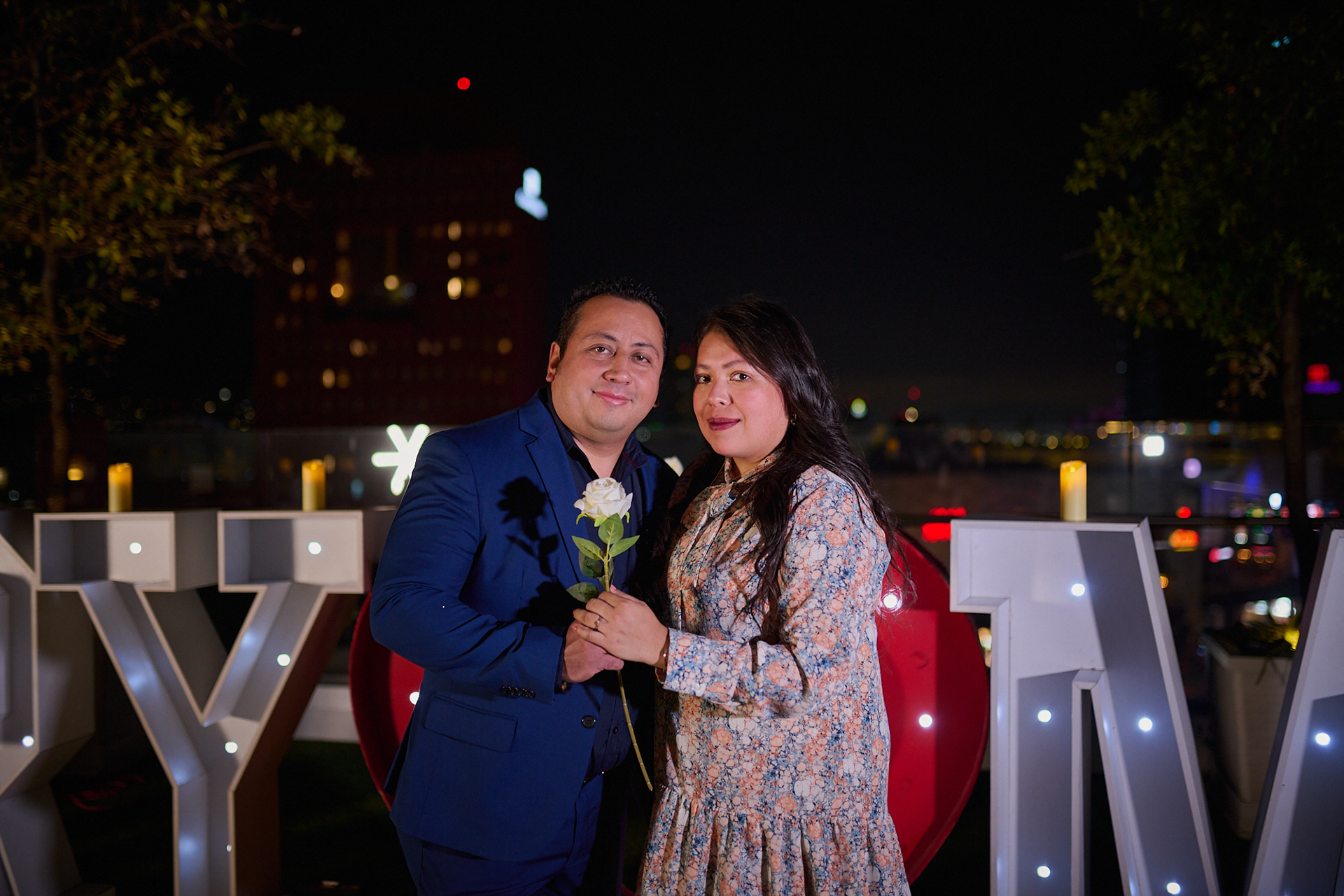 Pareja abrazada junto a letras luminosas de propuesta