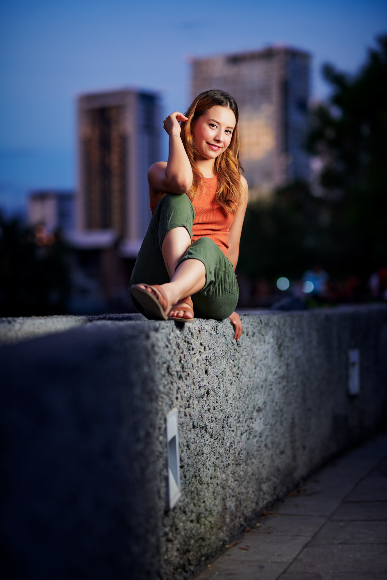 Mujer posando sentada sobre muro en ambiente urbano