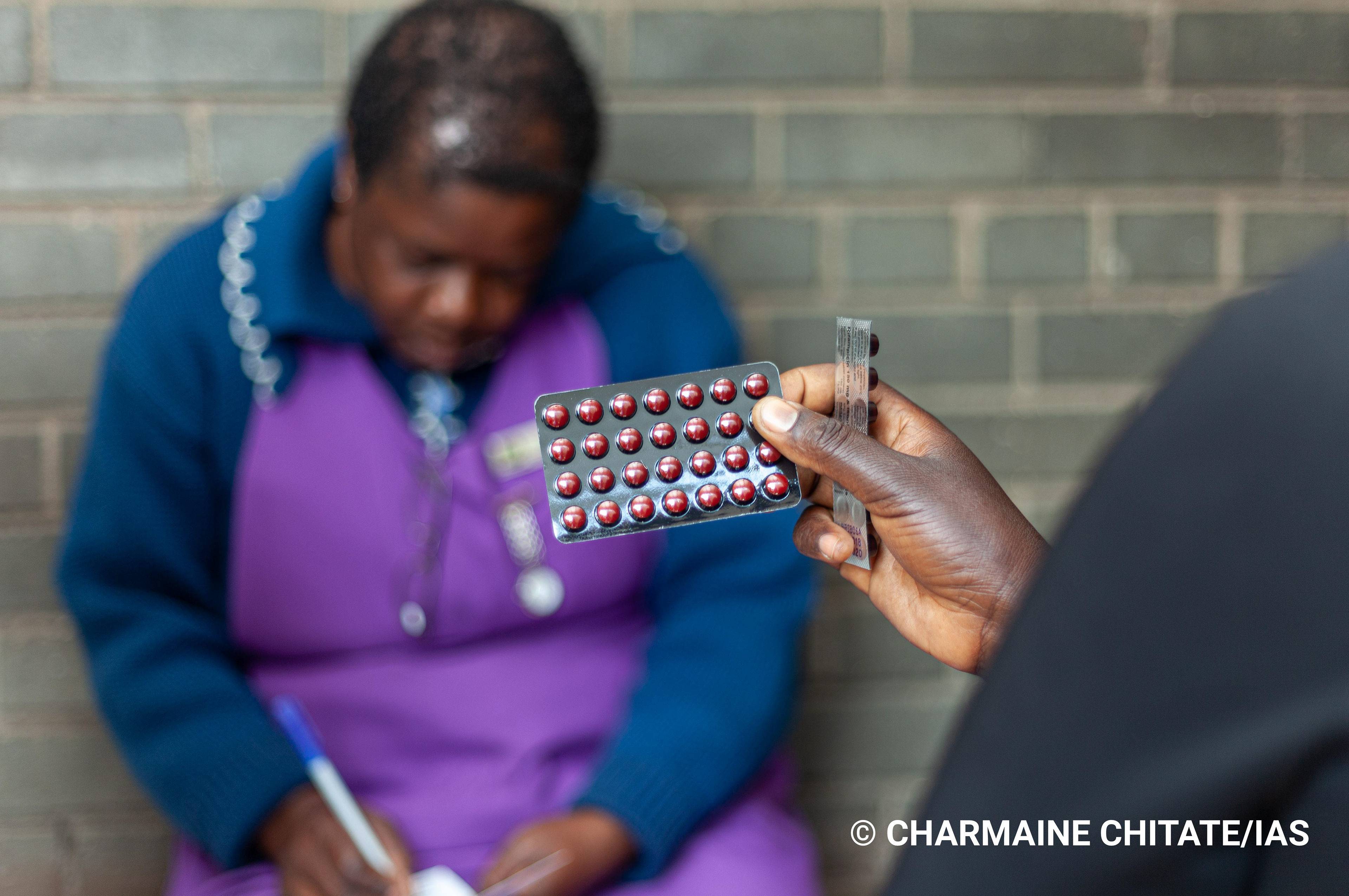 A patient at Rustanana Polyclinic holds their TB medication dispensed by Sr. Chikondo during a Media Field Trip facilitated by the International AIDS Society (IAS). (Photographer: Charmaine Chitate/IAS)