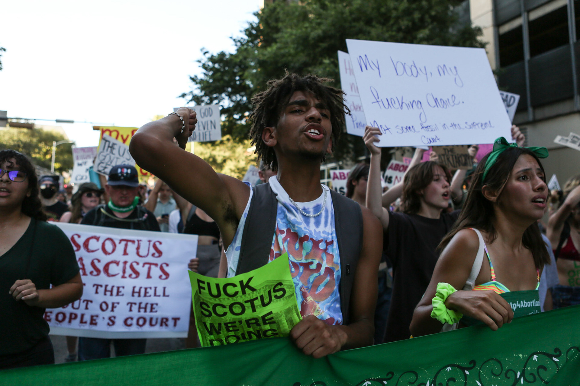 A man cheers holding a banner while walking to the Federal Courthouse Plaza.