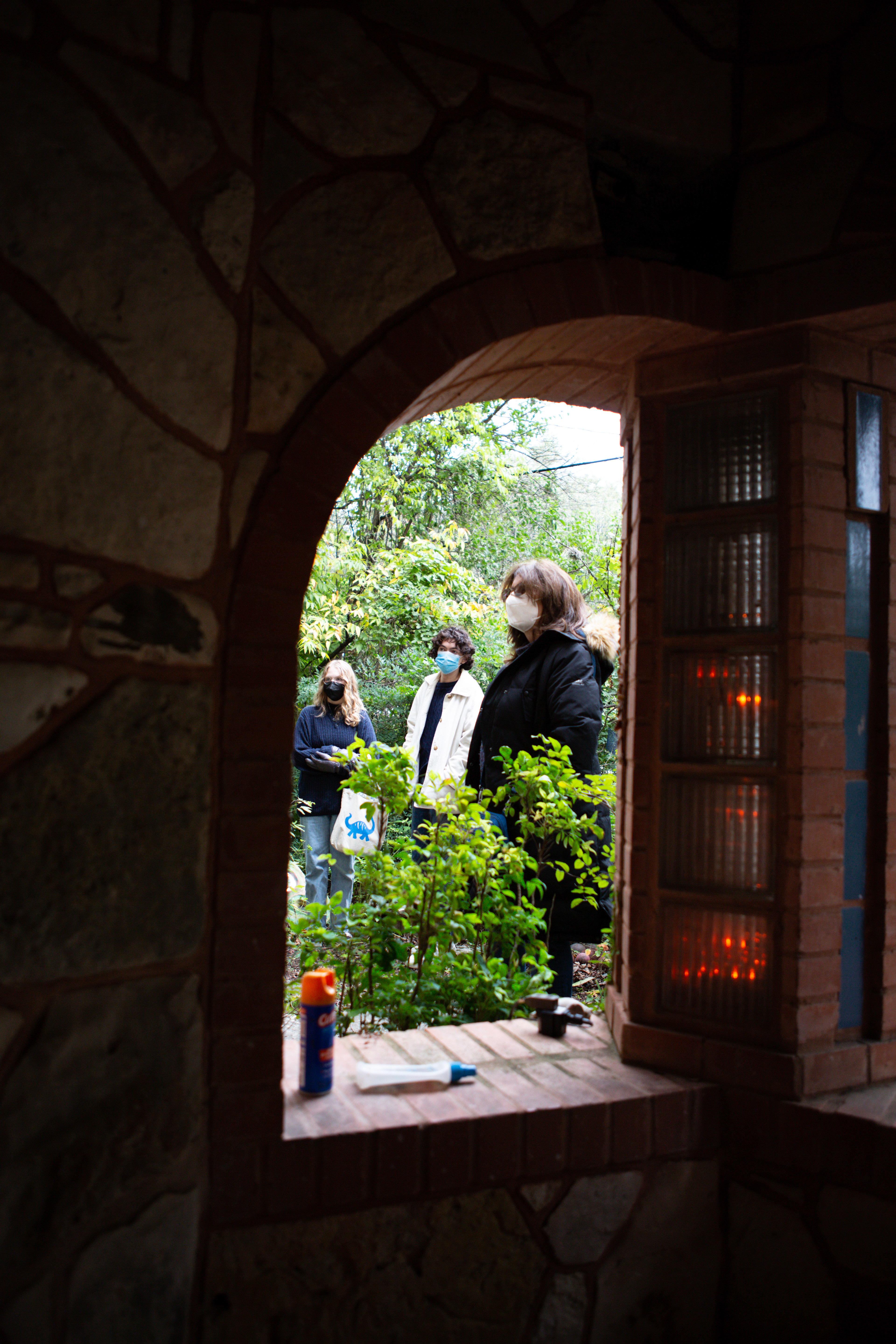 A group of people gather in his yard for a tour of his house. His front porch was expanded from its original design and now incorporates arches and mosaic tile work, one of his specialties.