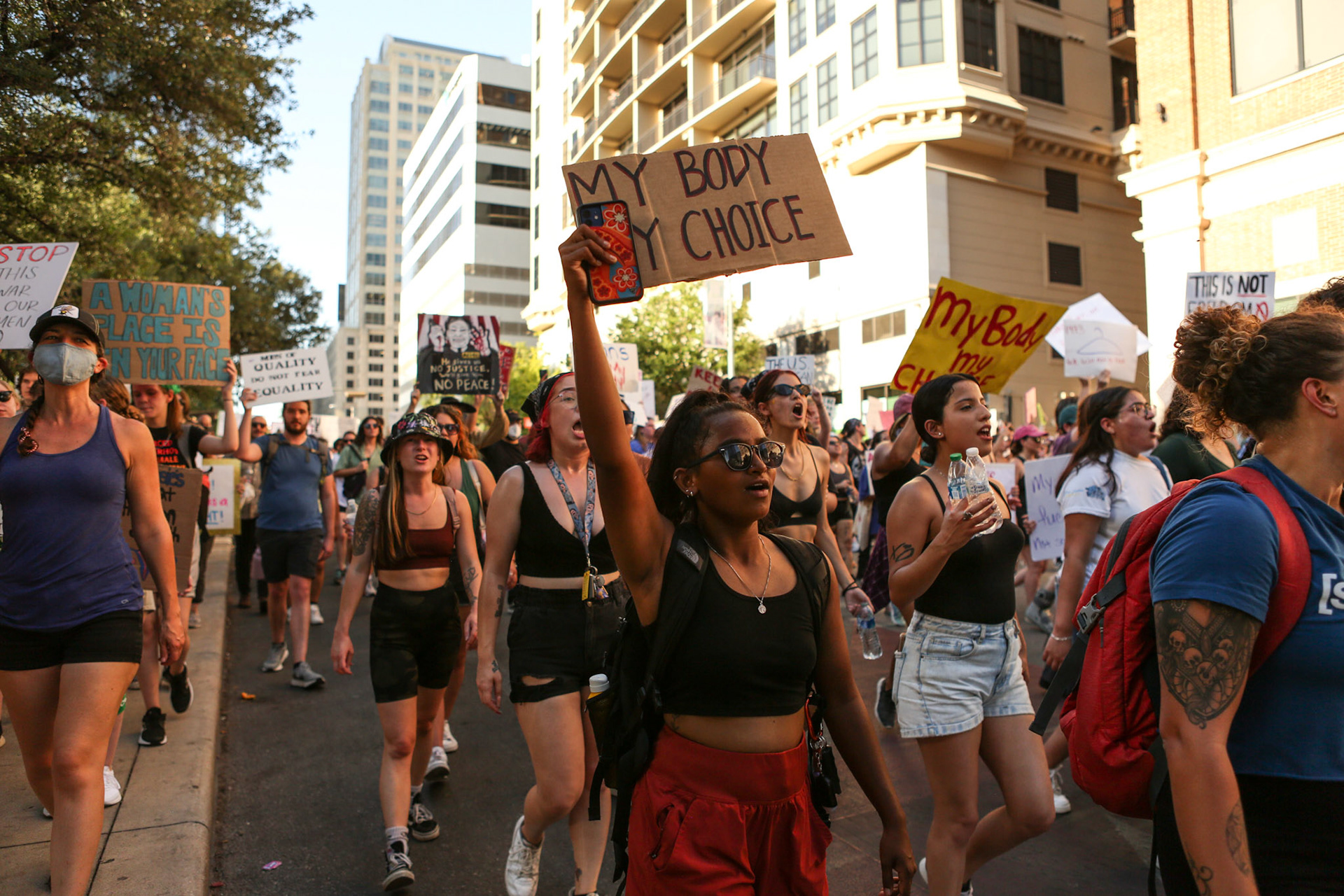 A girl holds up her sign in front of Federal Courthouse Plaza.