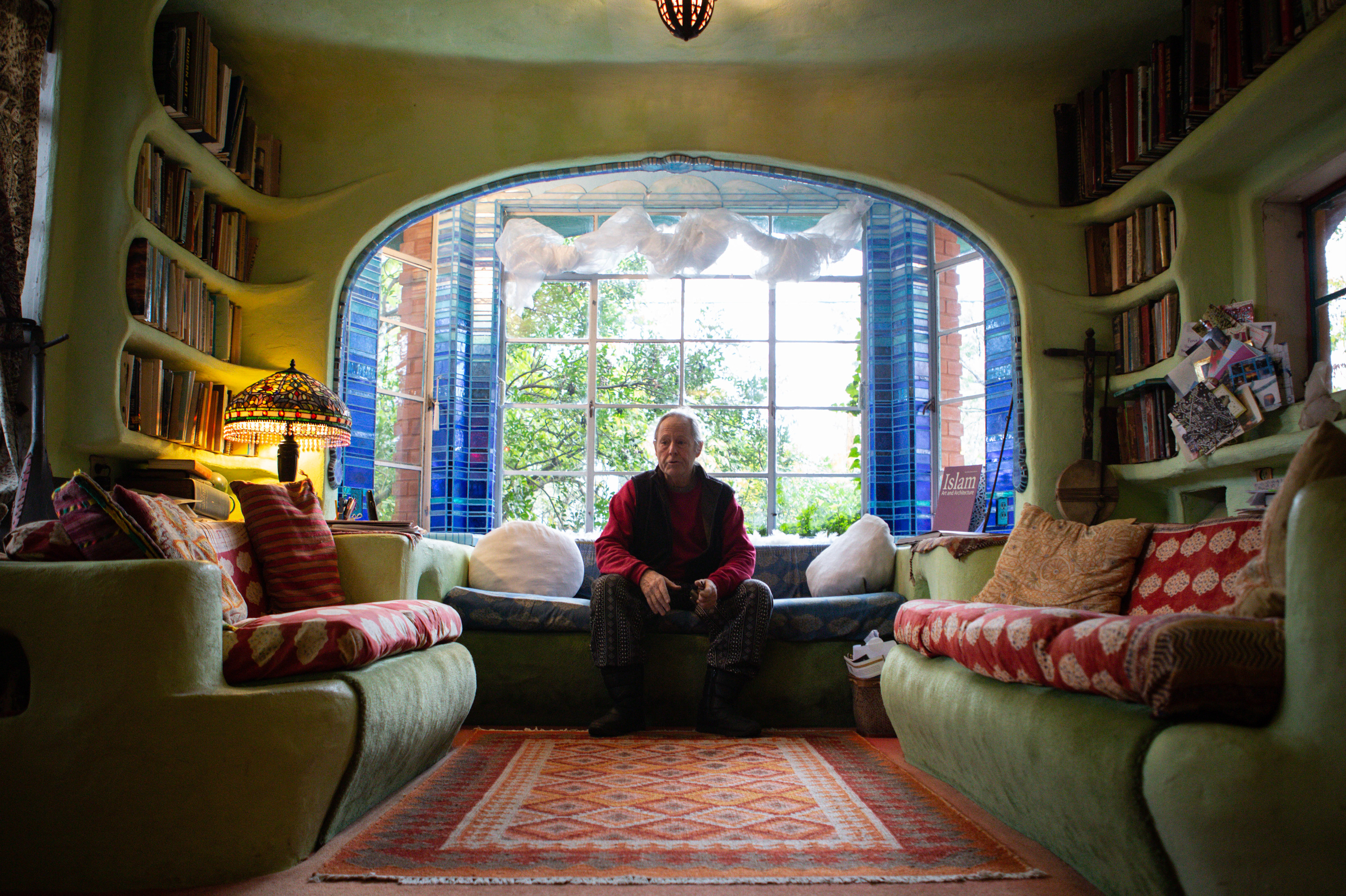 Talbot sits at the air altar in his living room, surrounded by books and decorations. His home has become a sanctuary for artists, locals and tourists alike.