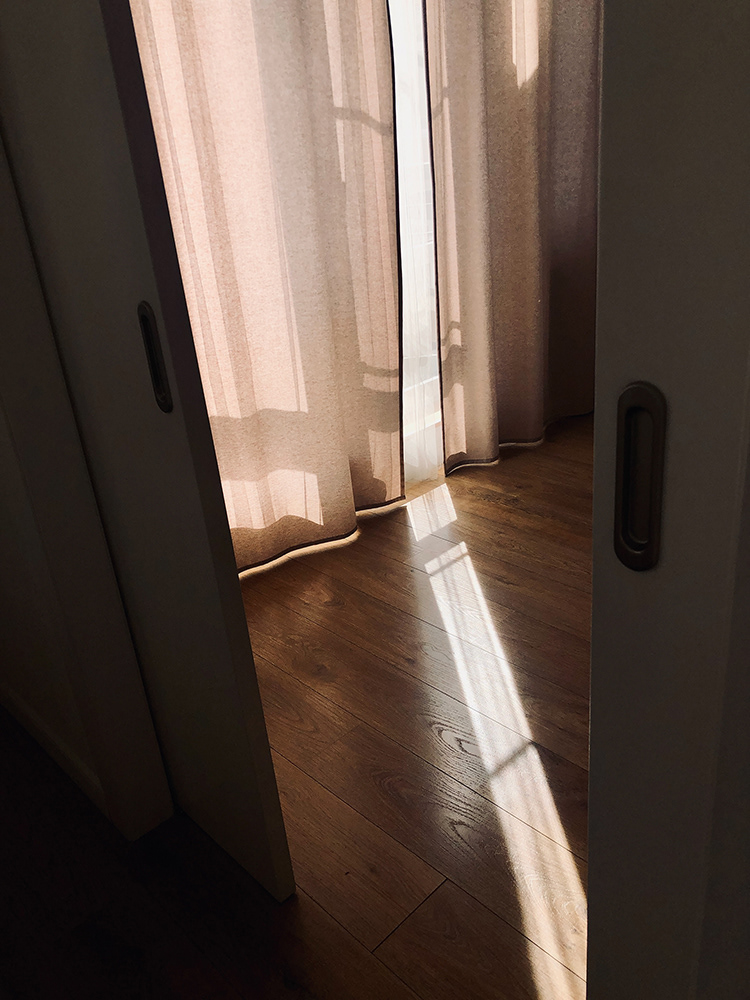 Ein Sonnenstrahl auf einem Holzboden zwischen Türen und Vorhängen, Oxana Guryanova