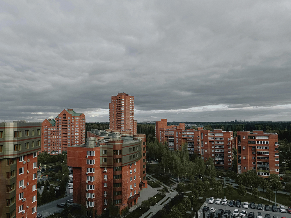 Blick auf hohe Wohngebäude aus rotem Backstein unter einem Himmel, Landschaft von Oxana Guryanova