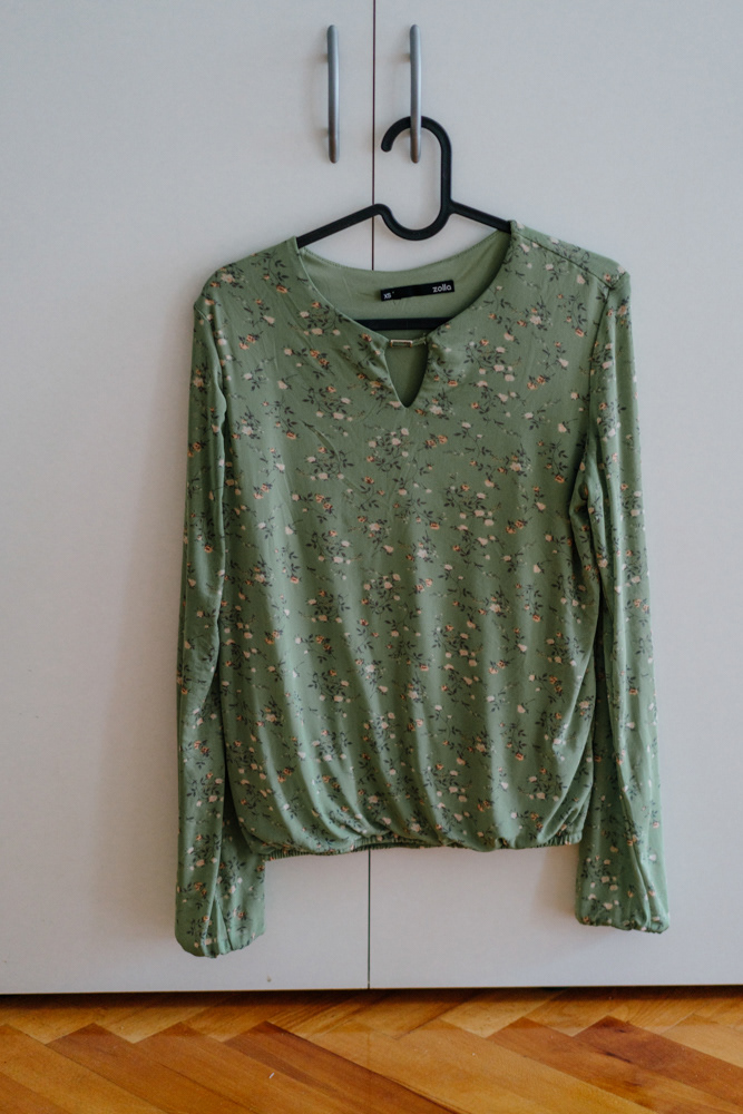 Grüne Bluse auf Kleiderbügel im Displaced-Projekt von Oxana Guryanova