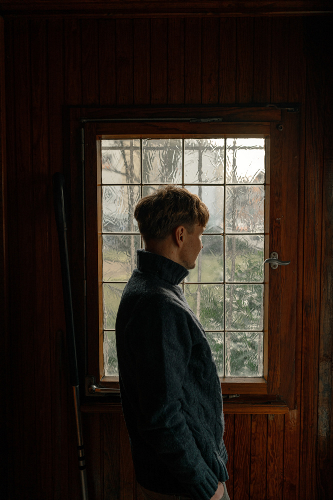 Mann blickt aus Fenster in Holzzimmer im Displaced-Projekt von Oxana Guryanova