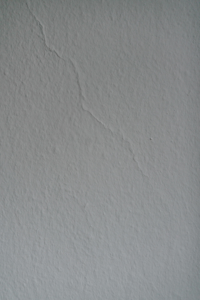 Graue Wand mit feinem Riss im Displaced-Projekt von Oxana Guryanova