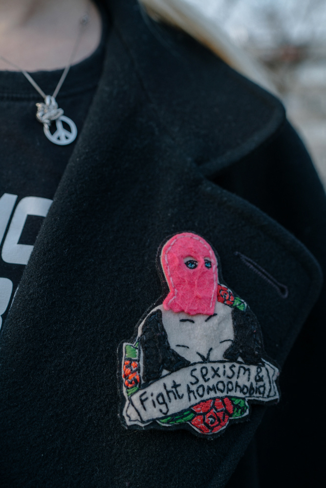 Schwarze Jacke mit „Fight sexism & racism“-Pin, von Porträtfotografin Oxana Guryanova.