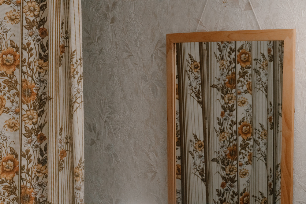 Blumenmuster-Vorhang und Spiegel im Displaced-Projekt von Dokumentarfotografin Oxana Guryanova