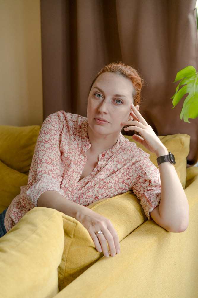 Nachdenkliche Frau auf gelbem Sofa im Displaced-Projekt von Dokumentarfotografin Oxana Guryanova