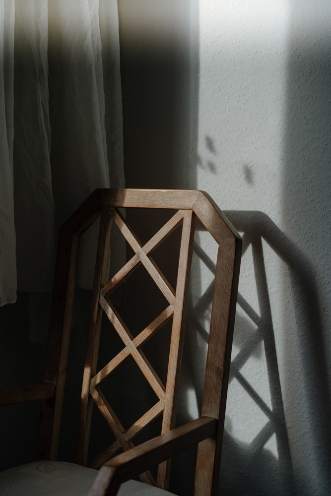Holzsessel mit Schatten vor Vorhang im Displaced-Projekt von Dokumentarfotografin Oxana Guryanova
