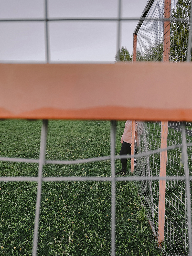 Eine menschliche Figur, die hinter einem Metallzaun vor dem Hintergrund steht, Oxana Guryanova