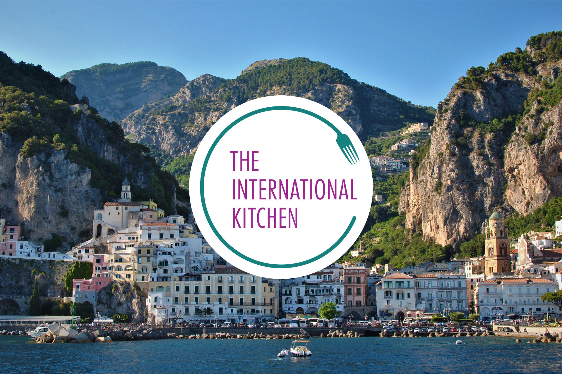 The International Kitchen logo in a white circle on top of a image of a coastal city in Italy.