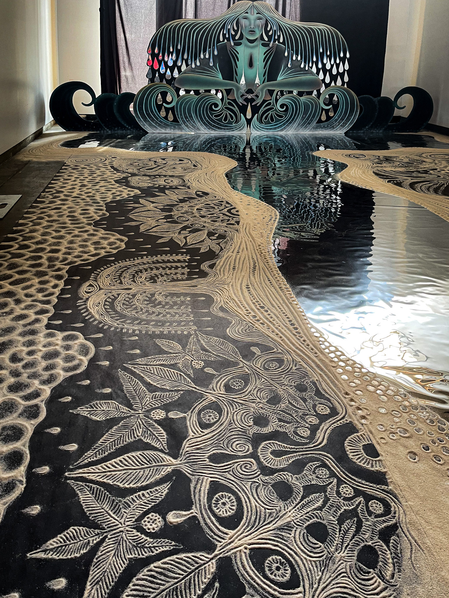 Sand drawings lining the river of the Mother of Waters installation. Pictured are drawings of kolo (sacred community), salmonberries, underground sentience, rain, and tears.